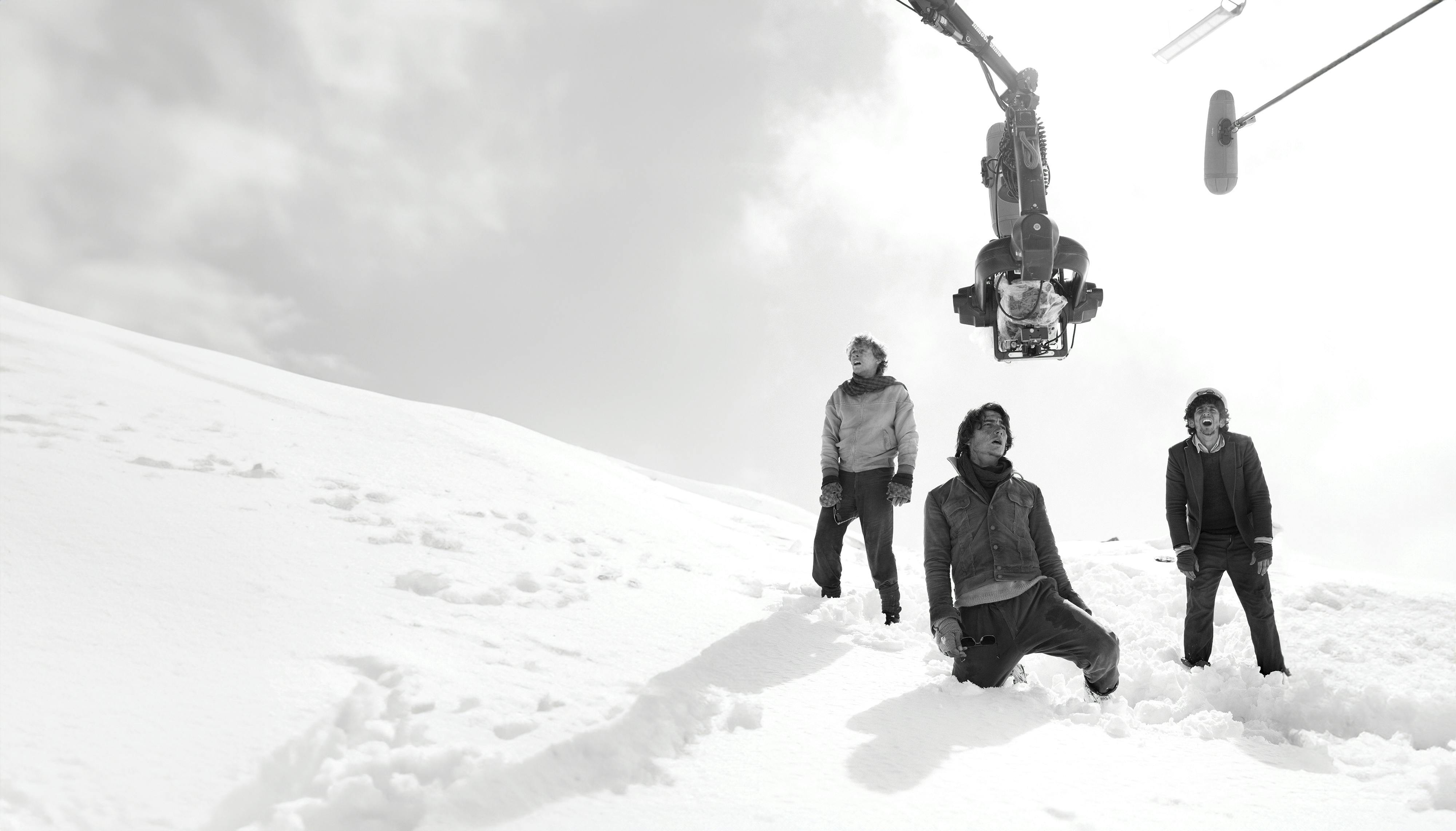 Santiago Vaca Narvaja, Enzo Vogrincic, and Tomás Wolf stand in the snow underneath a camera and boom mic.