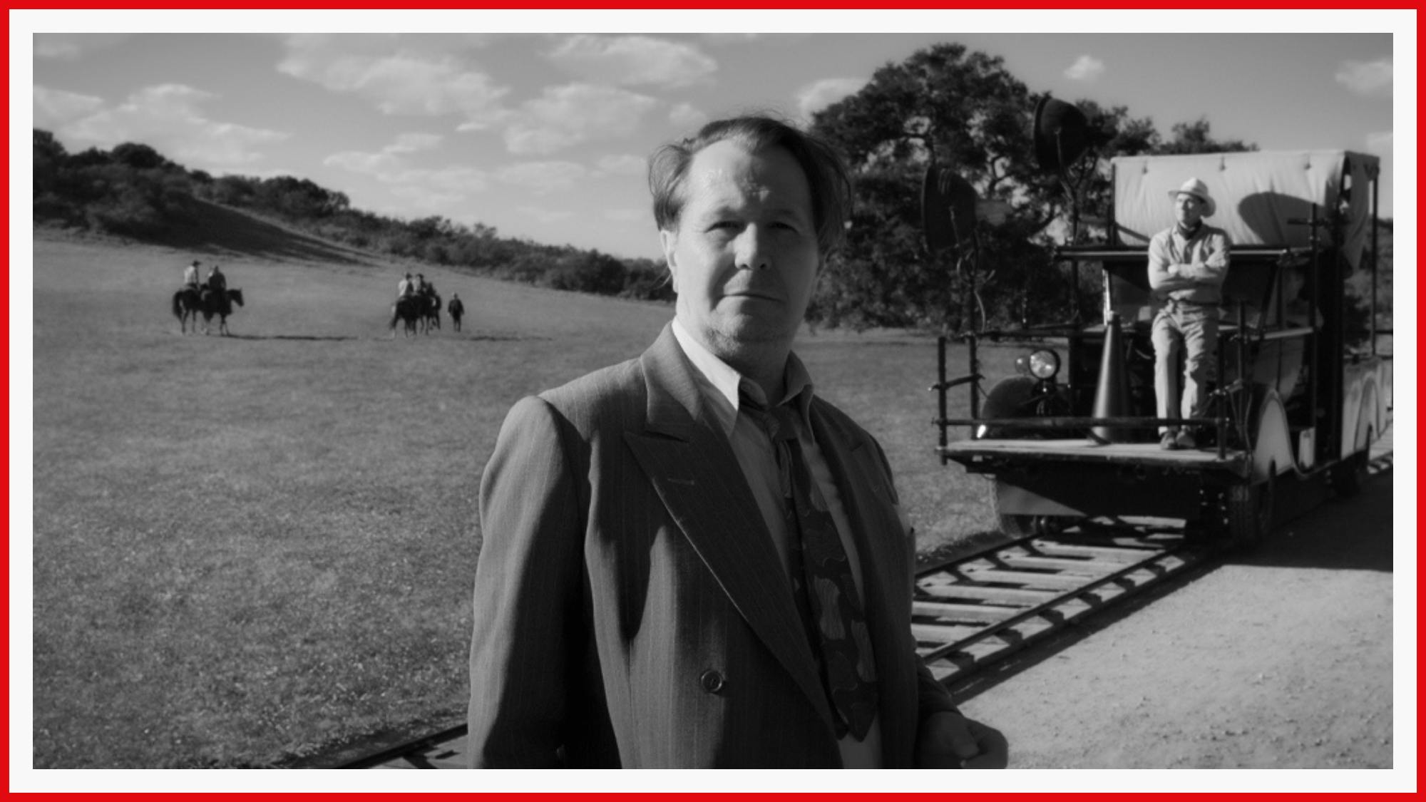 Gary Oldman finds himself in the middle of a meticulously composed shot as Mank. Fields stretch on in the back, Old Hollywood equipment for a dolly shot is visible to his right 