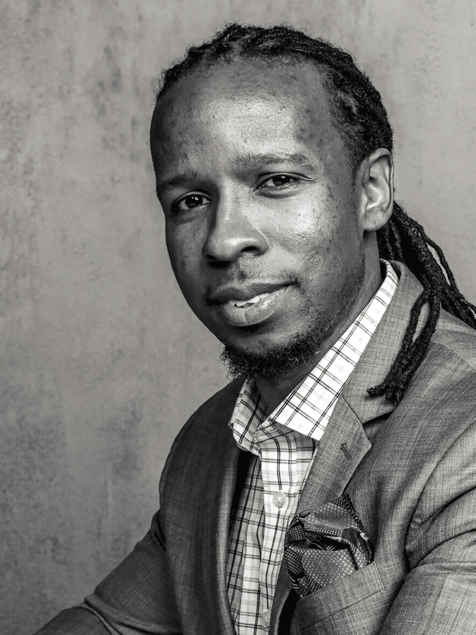 Dr. Ibram X. Kendi wears a checkered shirt under a blazer.