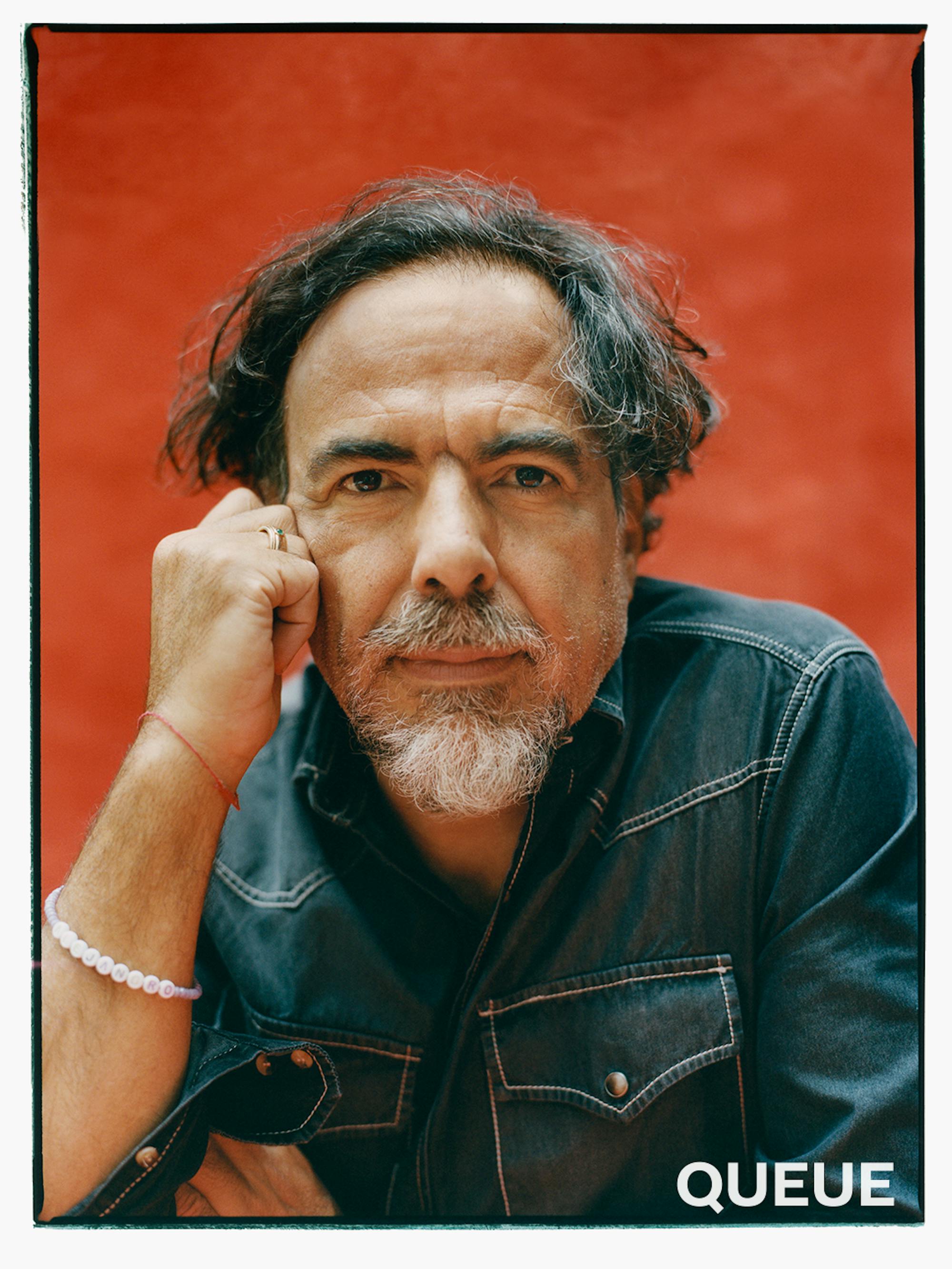 Alejandro González Iñárritu wears a denim short and rests his face against his fist.