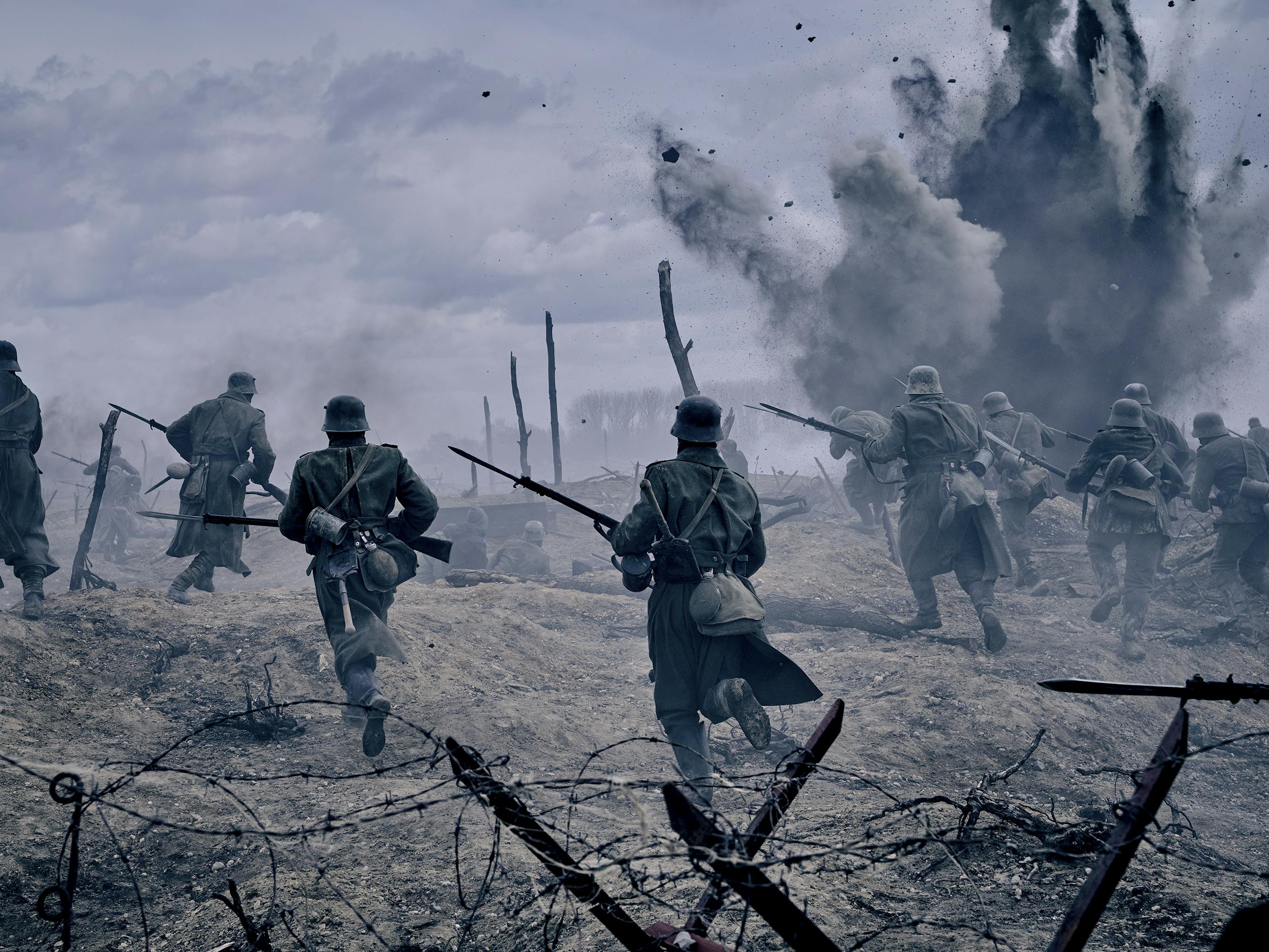 An explosive combat scene. Soldiers holding guns scatter about as a bomb explodes.