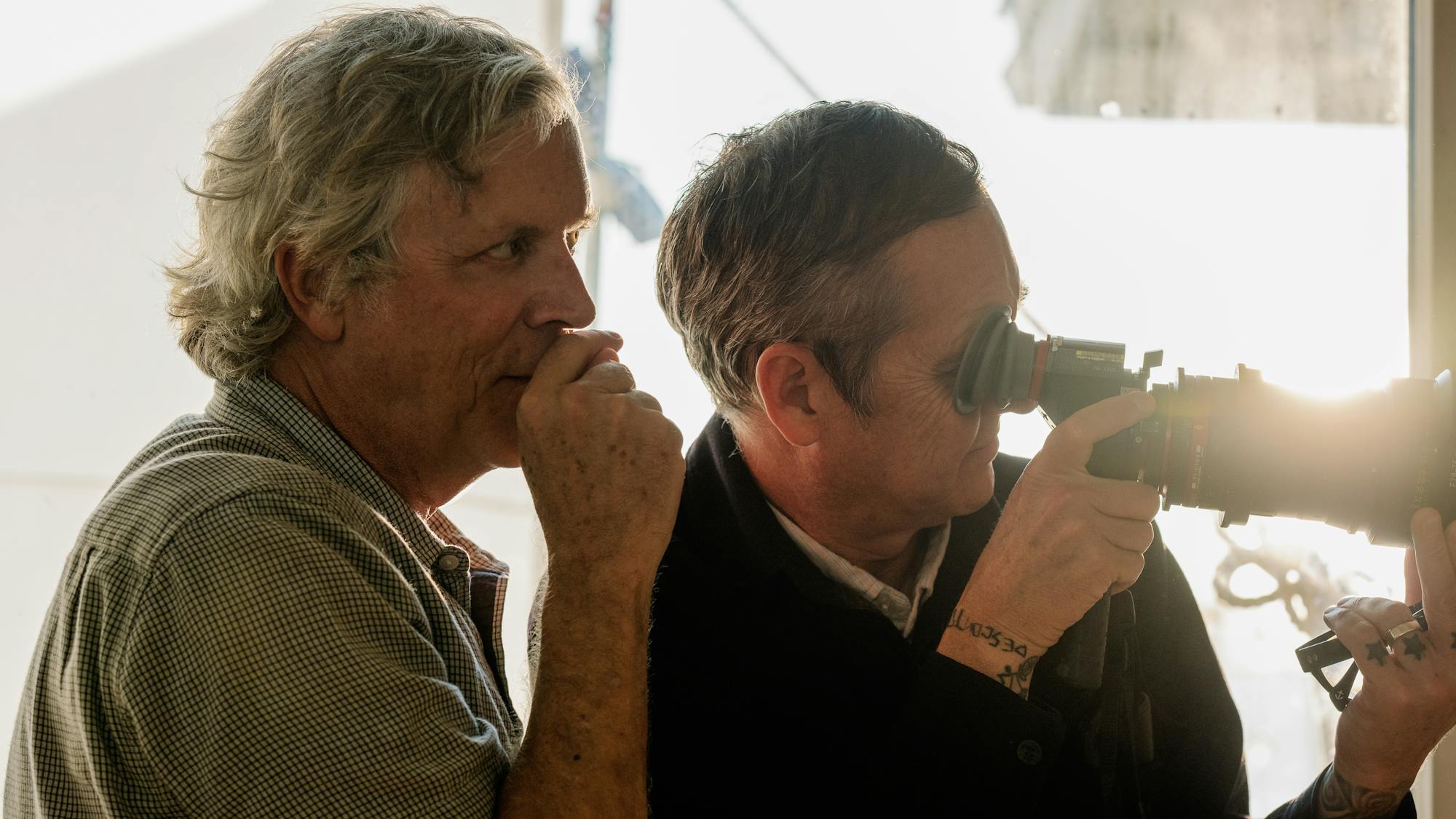 Todd Haynes stands behind Christopher Blauvelt as he looks through a camera.