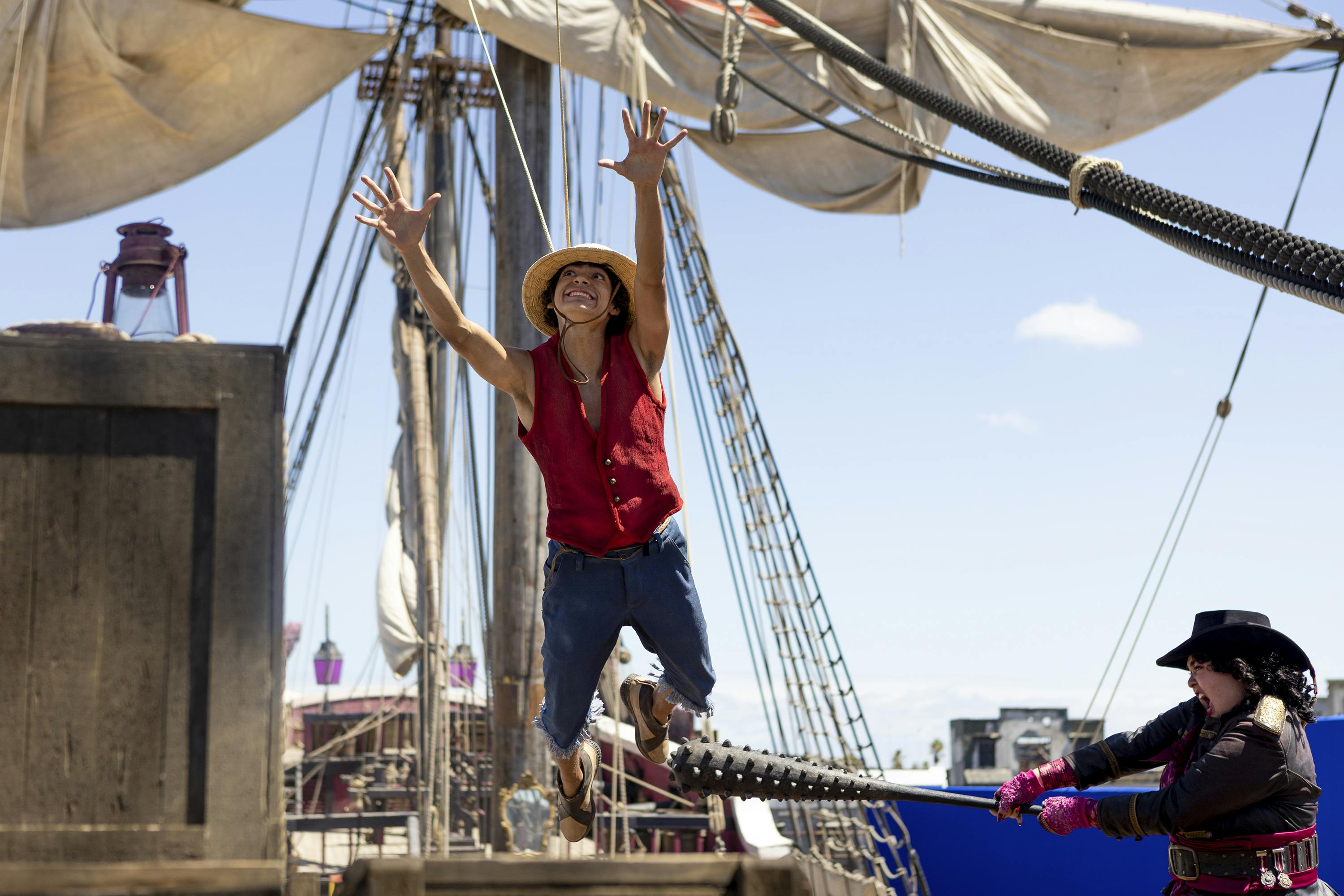 Monkey D. Luffy (Iñaki Godoy) jumps up towards a sail on a sailboat. 