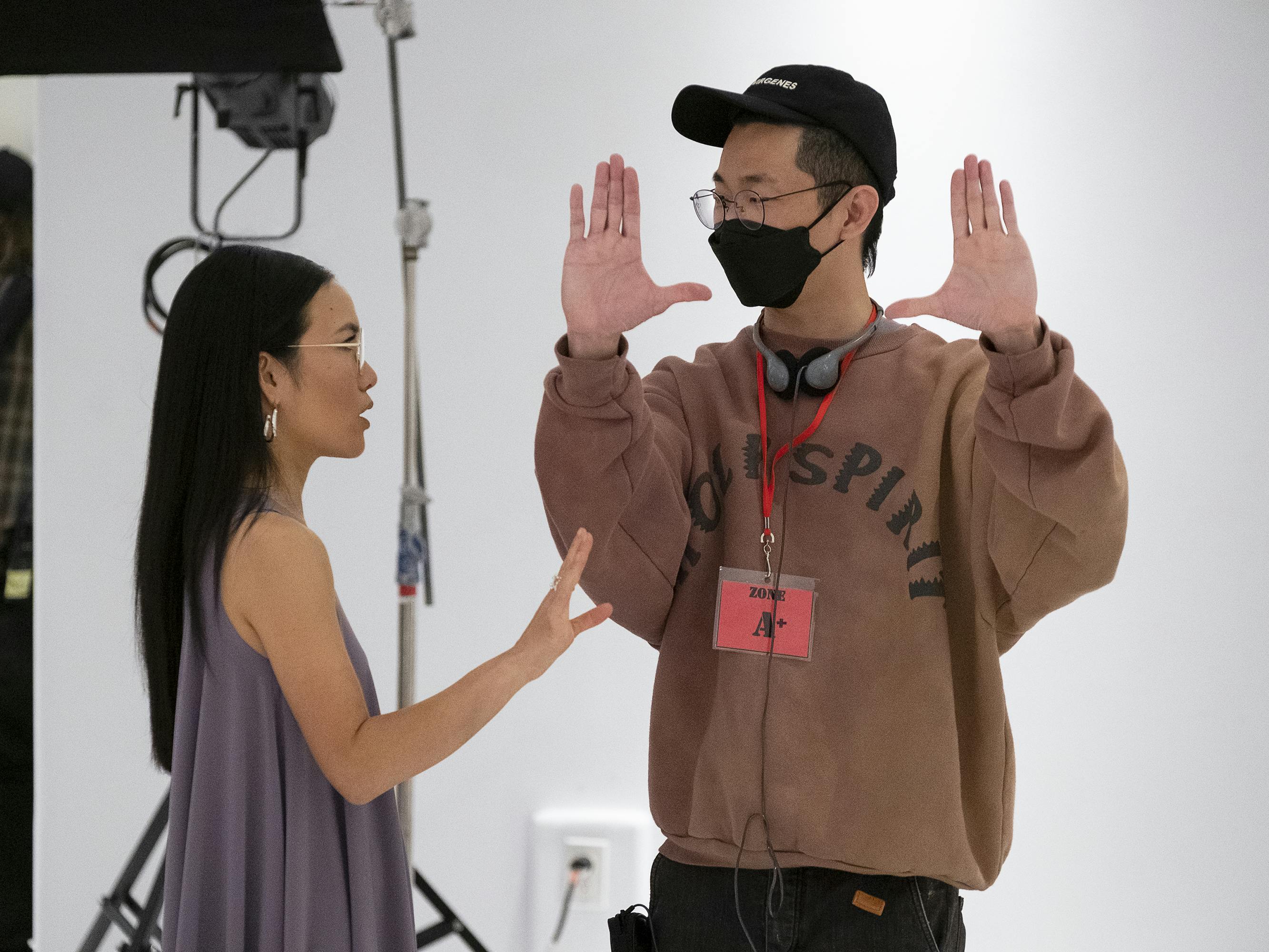 Ali Wong talks to Lee Sung Jin in a white-walled space. Wong wears a purple top and Lee wears a brown sweatshirt.