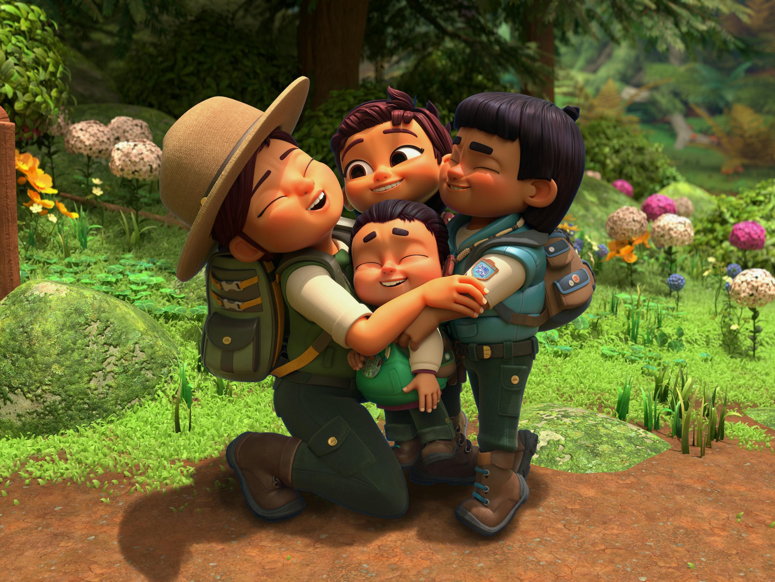 Mom gives her junior rangers a hug. Behind them is a green field dotted with pink and white flowers.