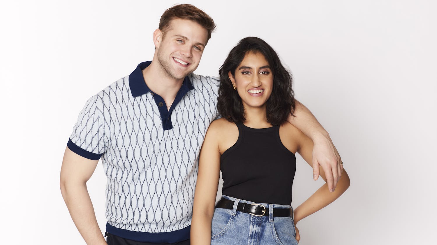 Leo Woodall and Ambika Mod pose together against a white background. He wears a patterned polo shirt and dark pants. She wears jeans and a black racerback tank.
