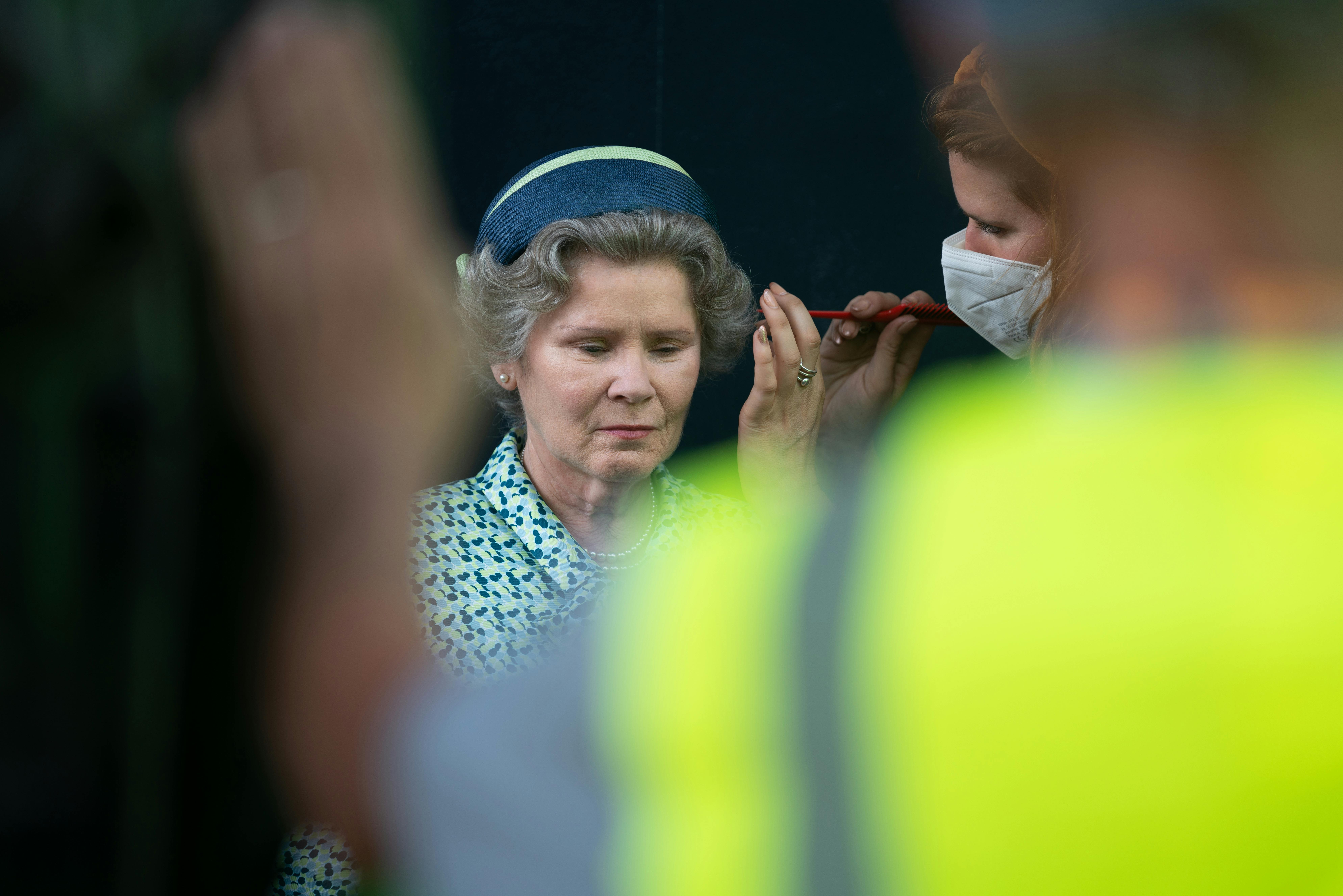 Someone touches up Imelda Staunton's hair in a solemn moment.