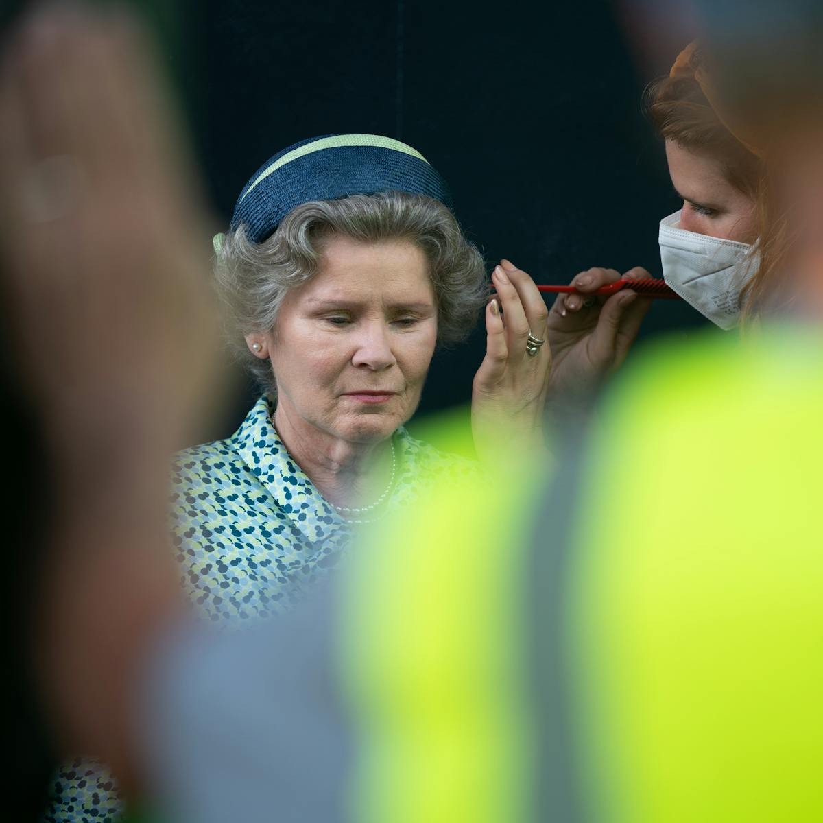 Someone touches up Imelda Staunton's hair in a solemn moment.