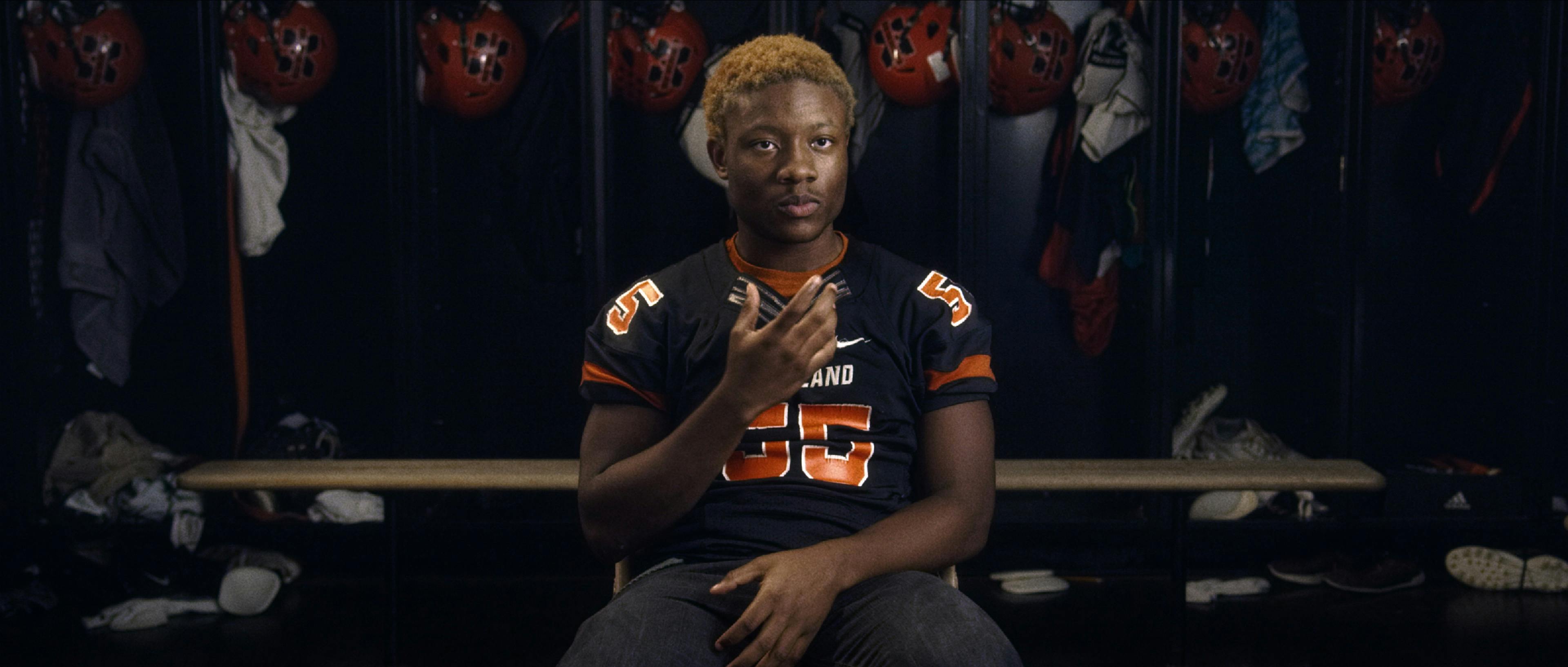Amaree McKenstry-Hall wears his MSD black and orange jersey and sits in a lockeroom. 