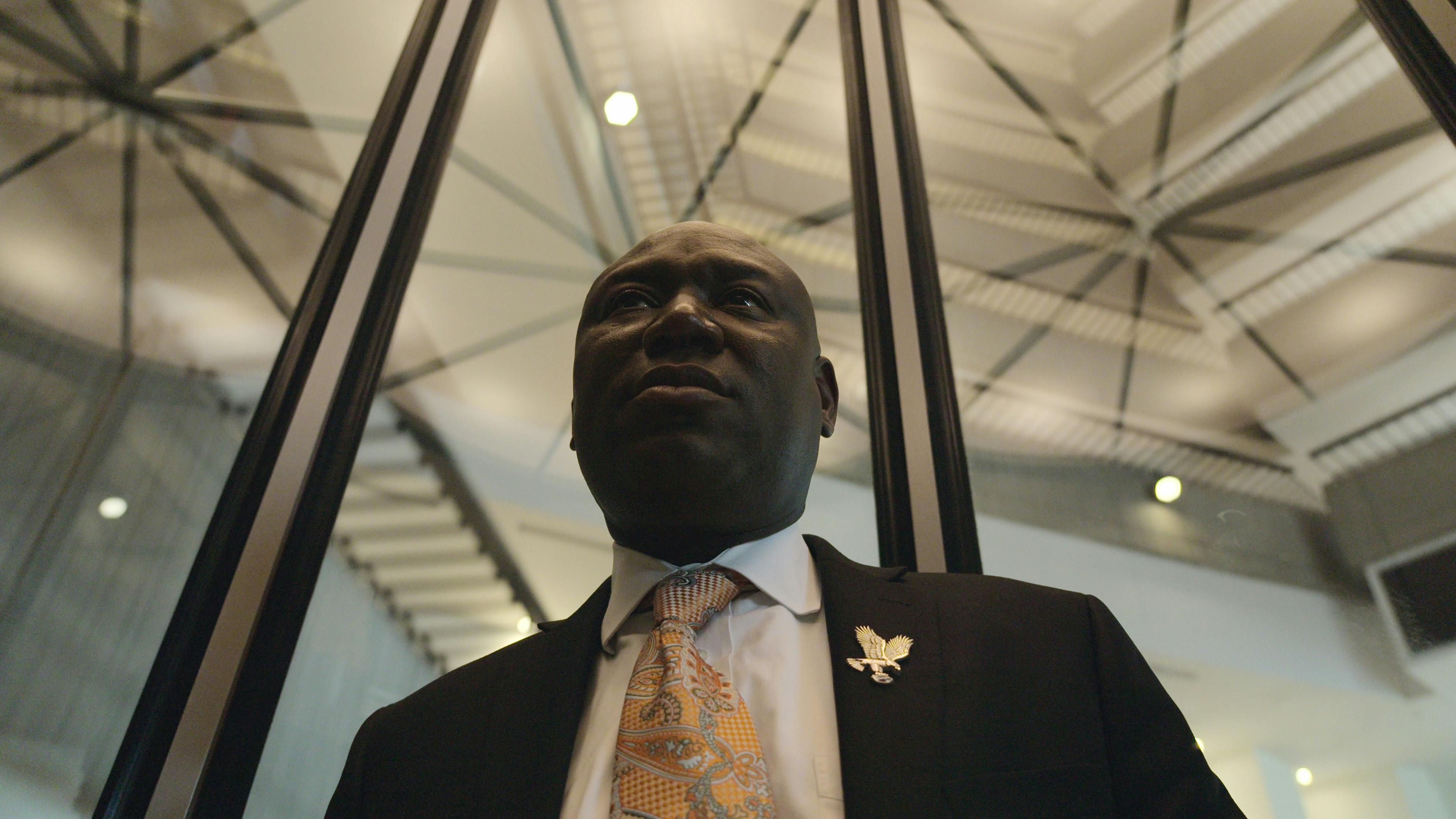 Ben Crump wears a dark blazer, yellow tie, and white shirt. 