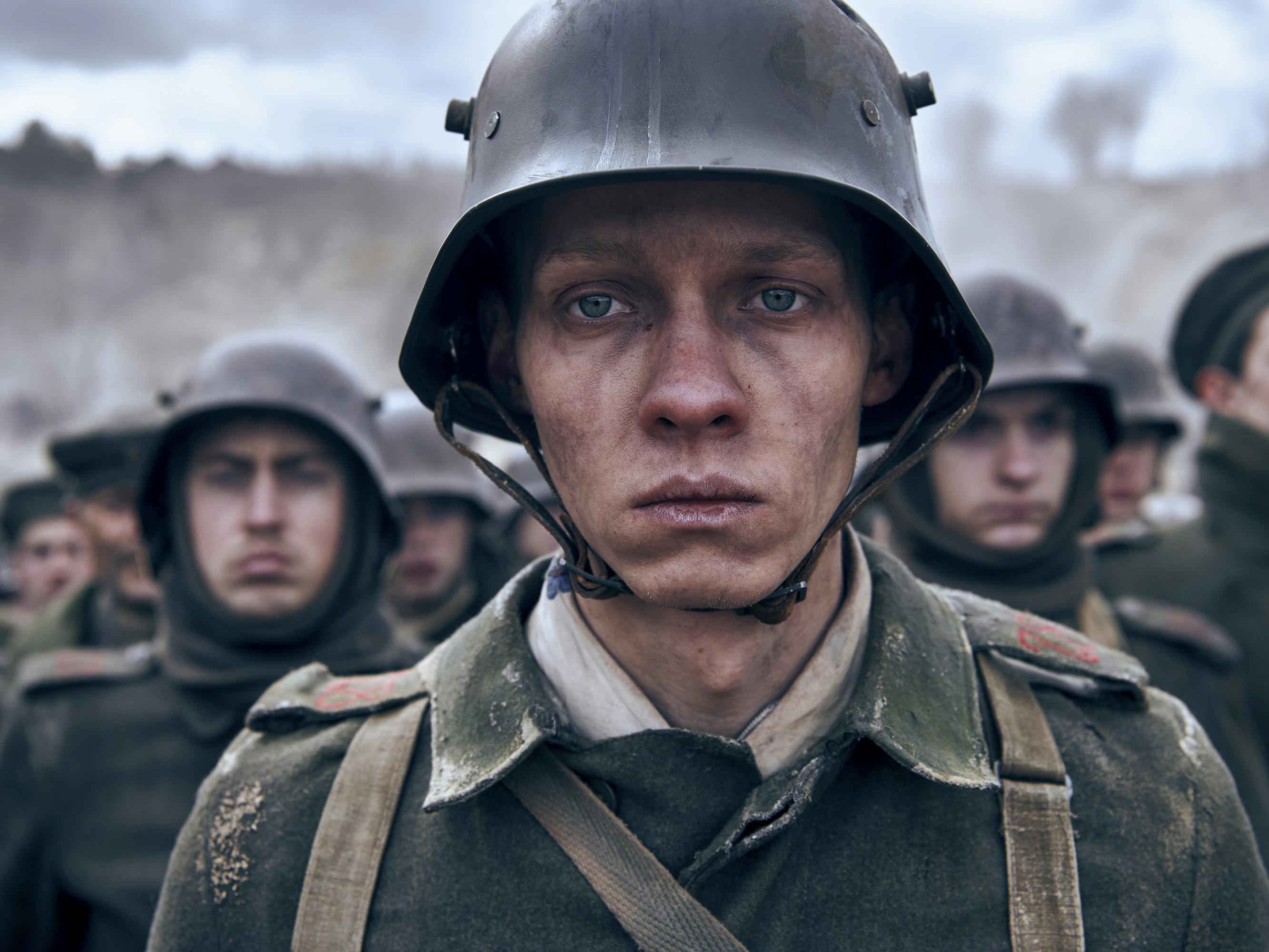 Paul Bäumer (Felix Kammerer) looks beleaguered in a crowd of soldiers wearing green uniforms and helmets.