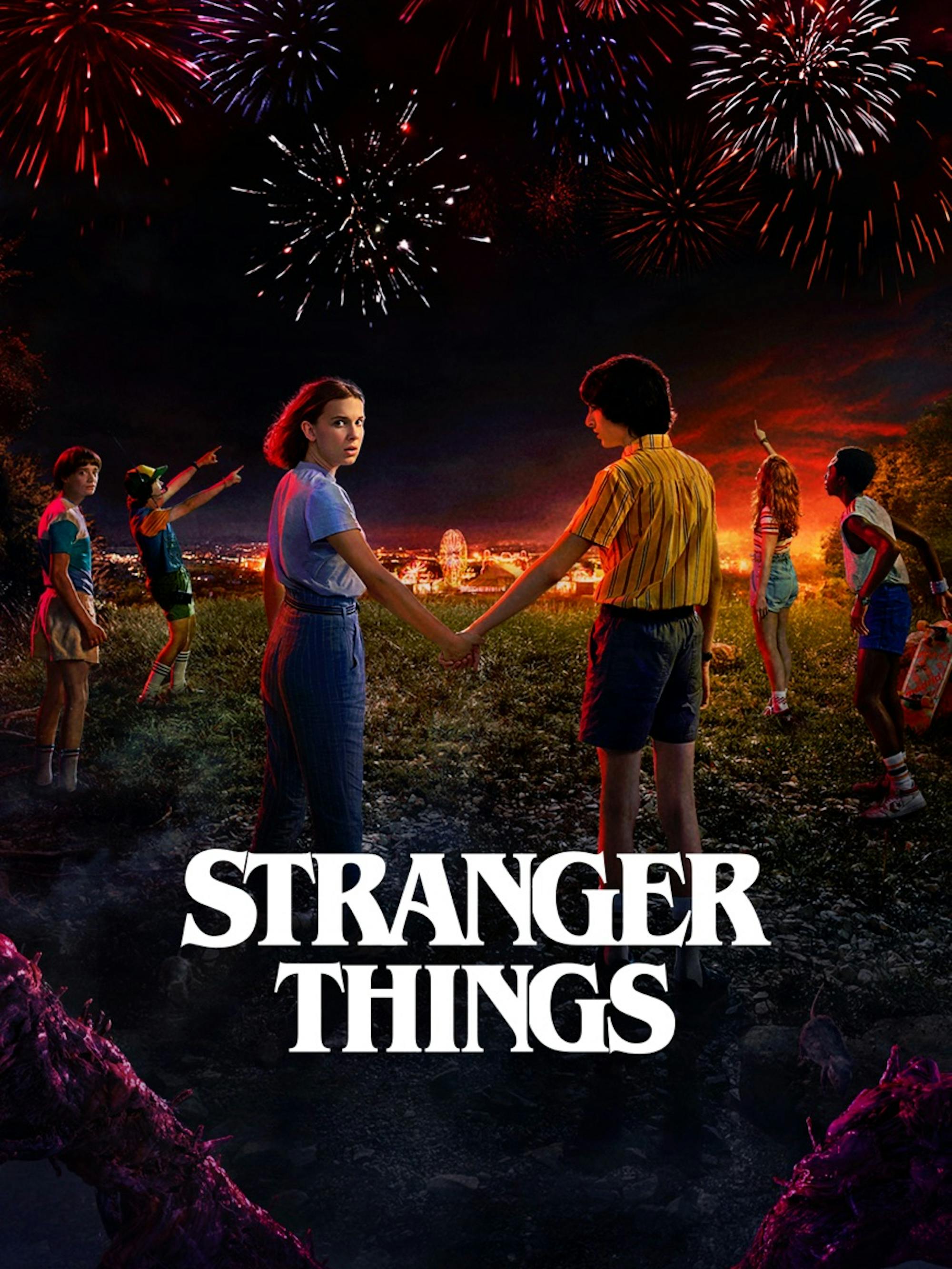 In a field lit from above by fireworks, 5 teens look up to the sky. One, as she holds another character’s hand, looks back at the camera with a sinister expression. The title reads below in white.