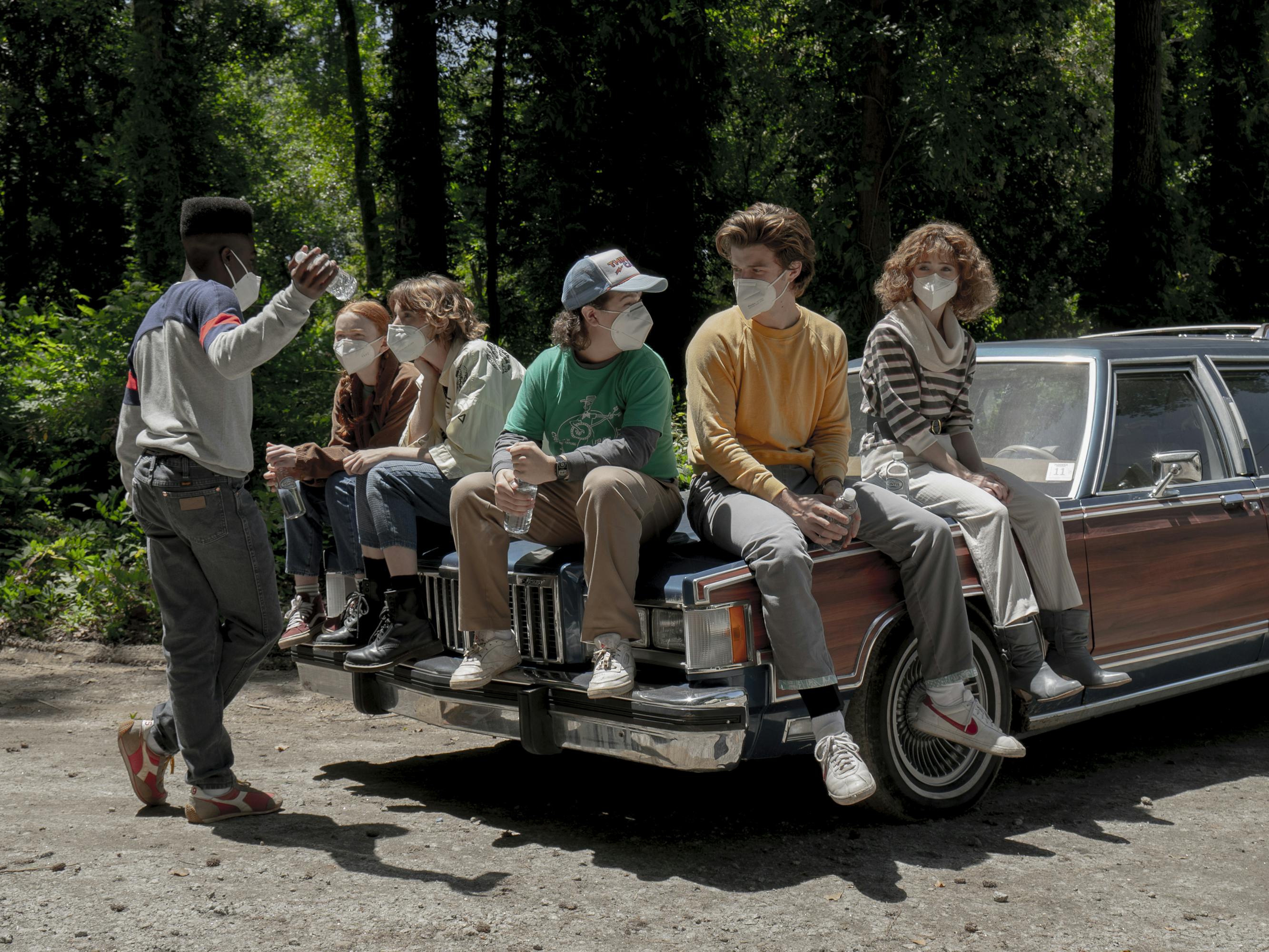 The Stranger Things cast hangs out on an old car.