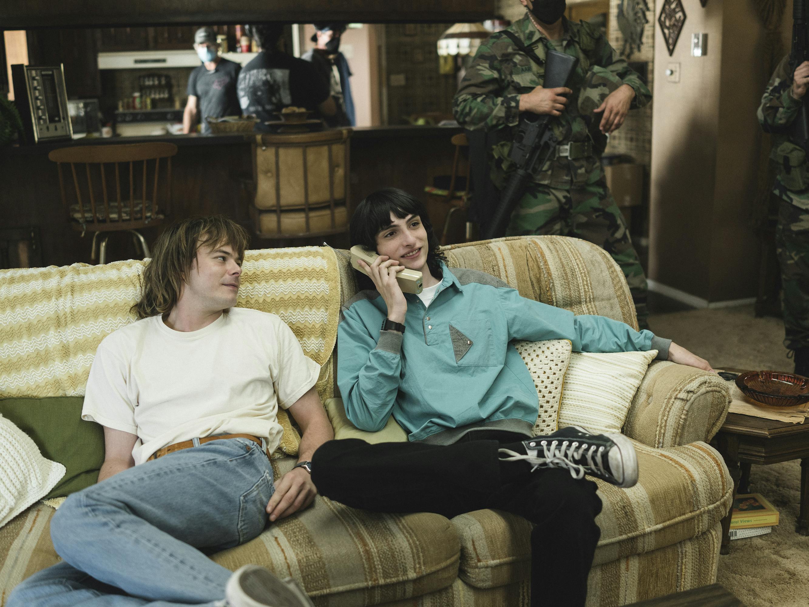 Jonathan Byers (Charlie Heaton) and Mike Wheeler (Finn Wolfhard) sit on a yellow striped couch.