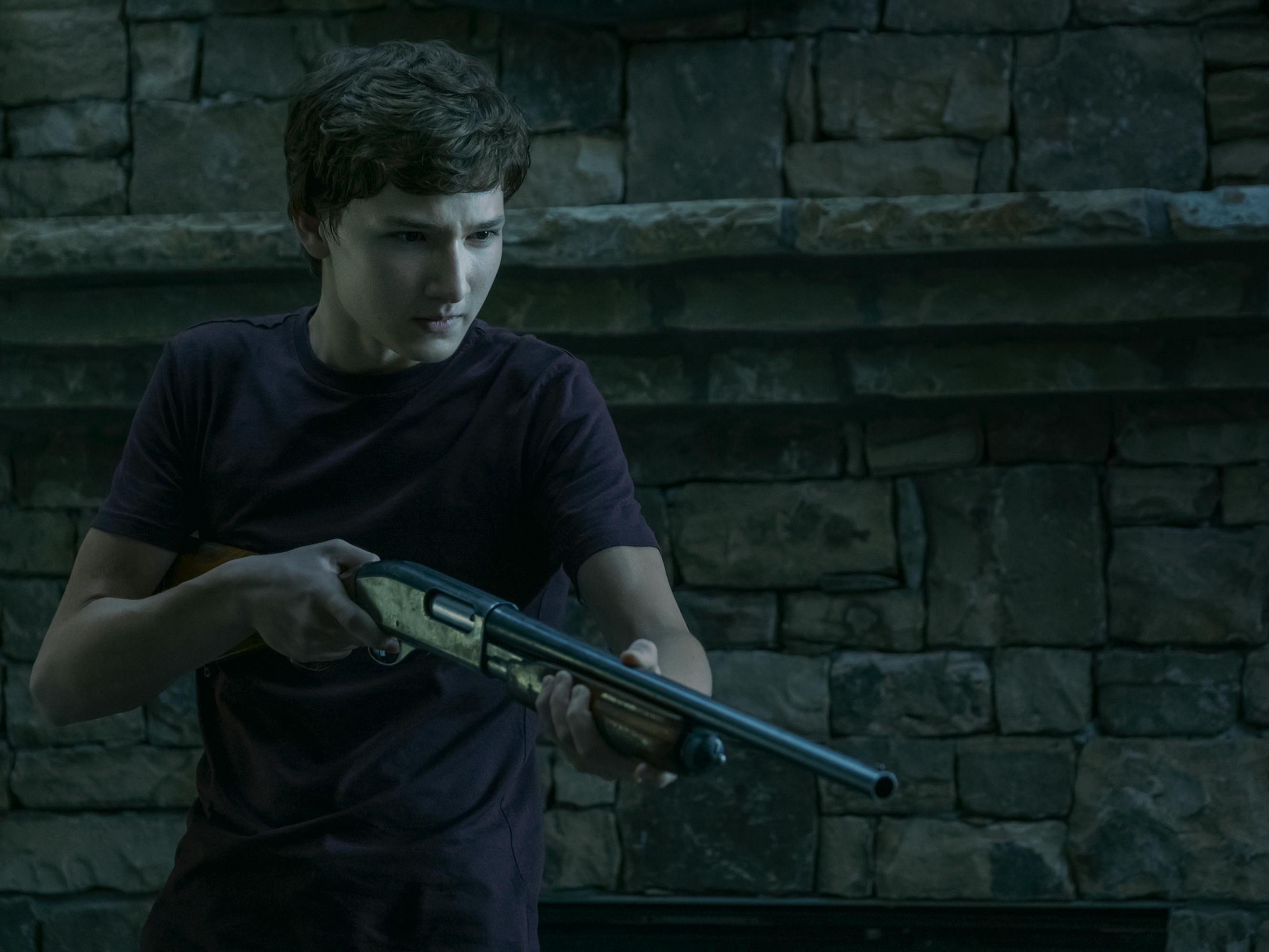 Jonah Byrde (Skylar Gaertner) holds a gun and wears a dark t-shirt.