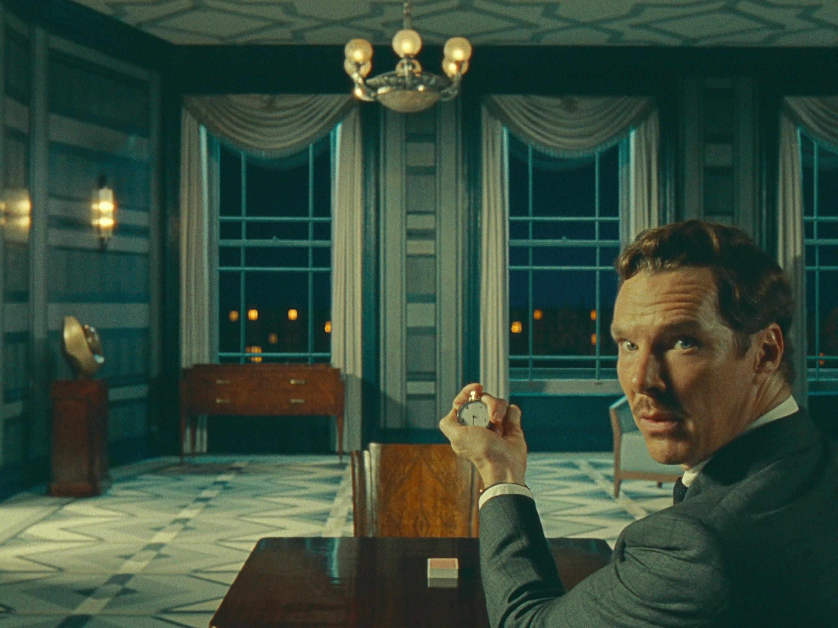 Henry Sugar (Benedict Cumberbatch) holds up a stopwatch in a blue, ornate room.