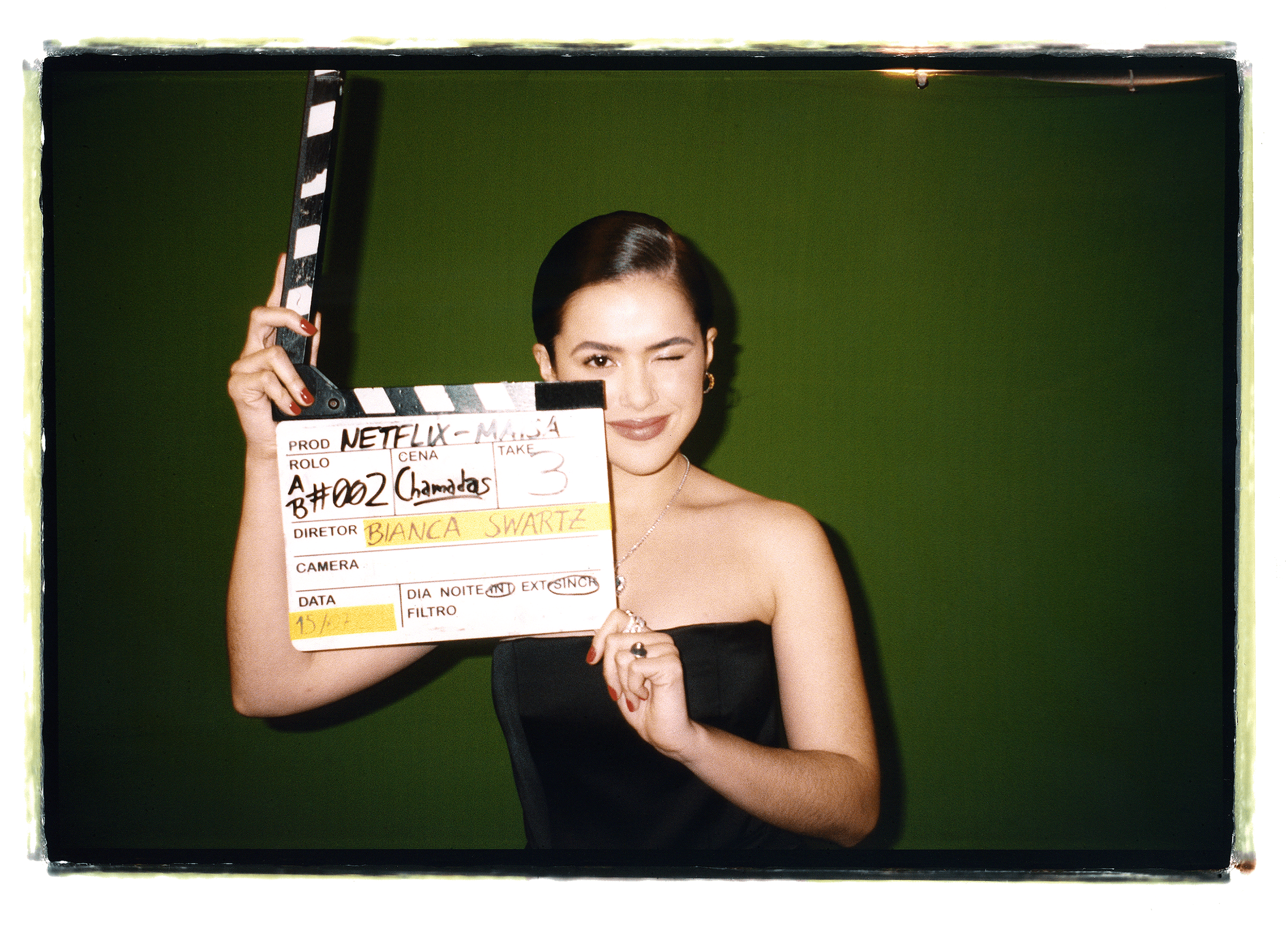 Maisa Silva wears a black tube top and holds a clapperboard.