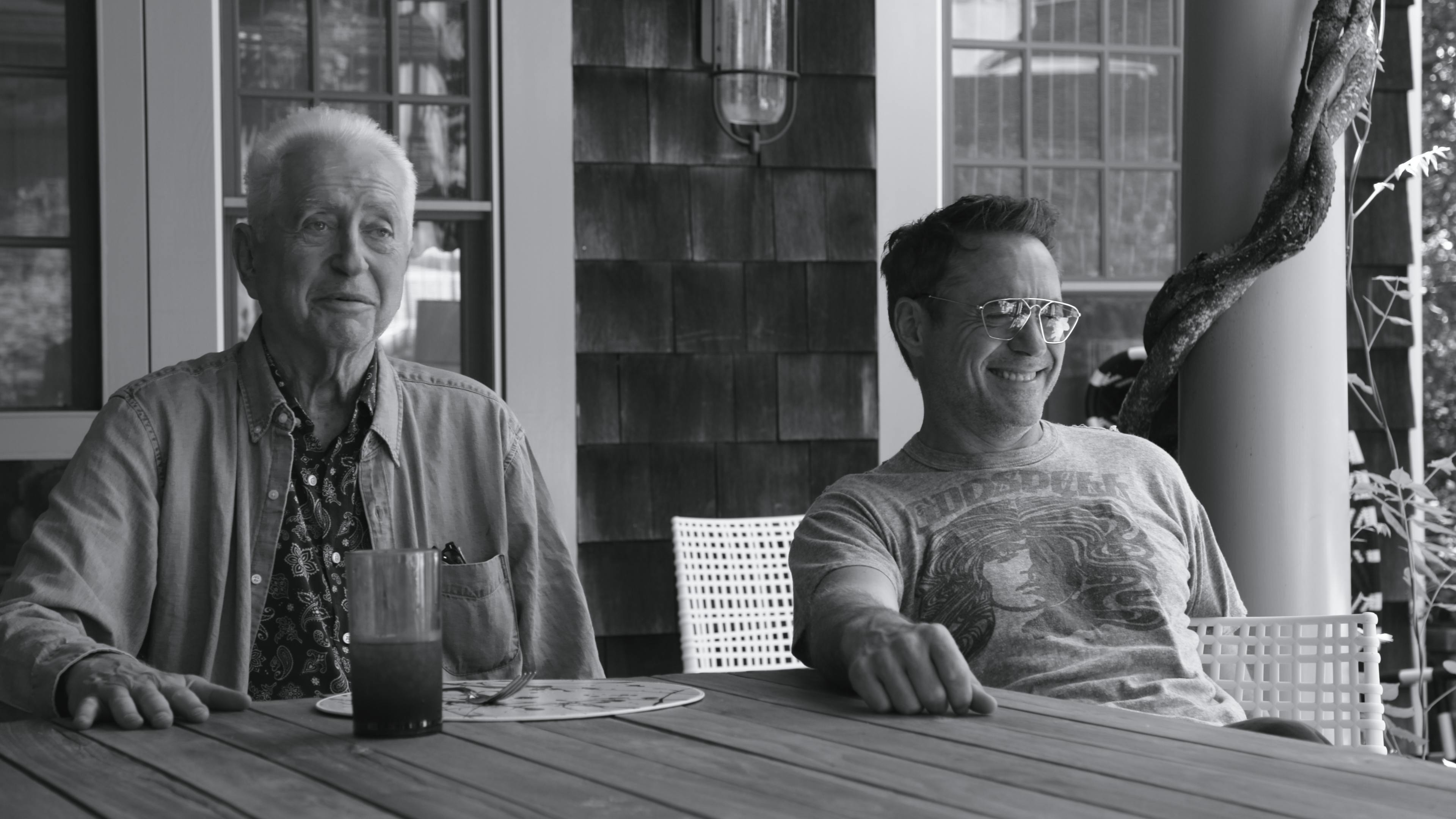 Robert Downey Sr. and Robert Downey Jr. sit at a table in a black-and-white photo.