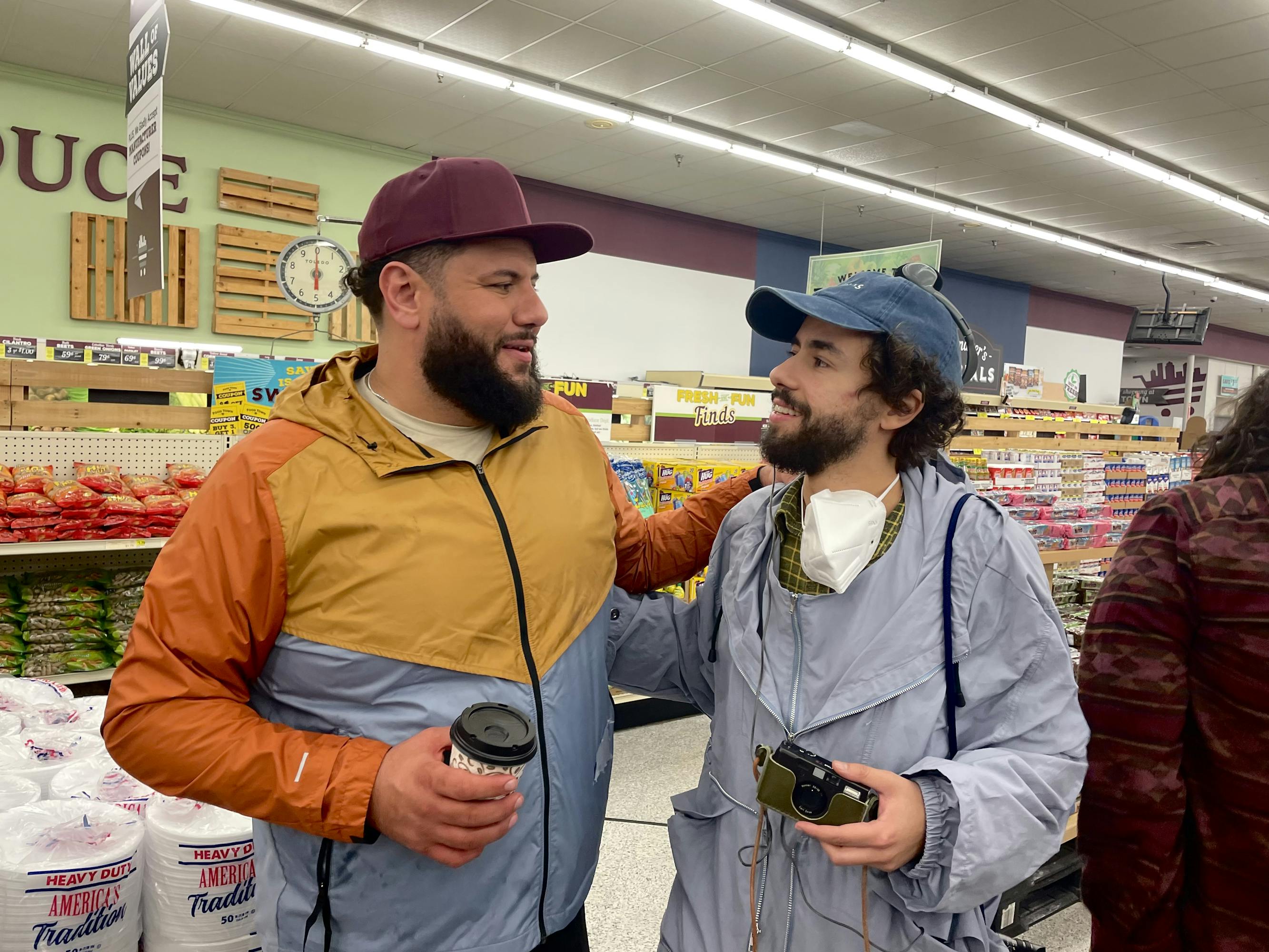 Mo Amer and Ramy Youssef stand together in a grocery market. They clap each other on the back and look very happy, making for a very sweet picture!