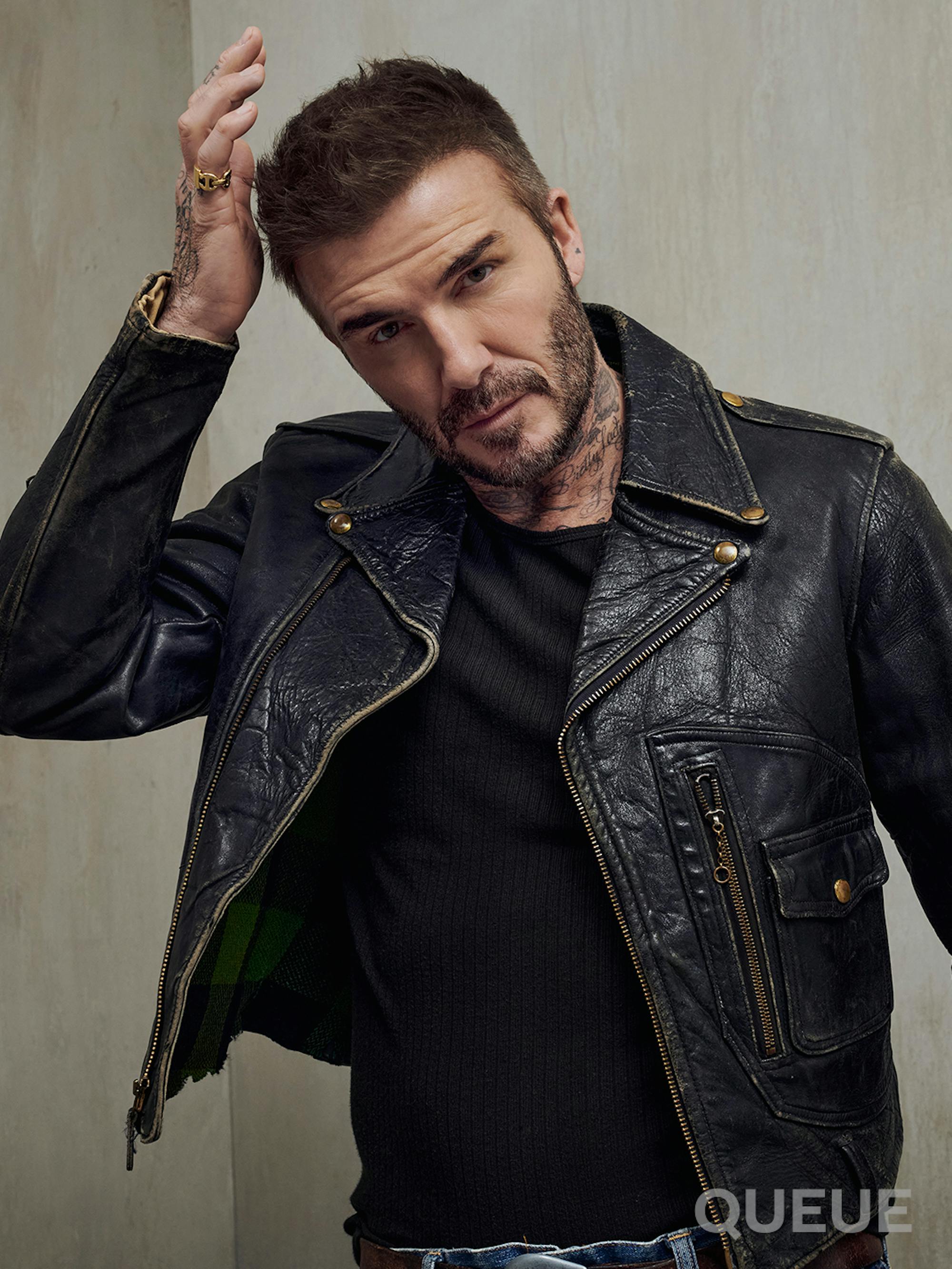 David Beckham wears a black shirt under a black leather jacket.