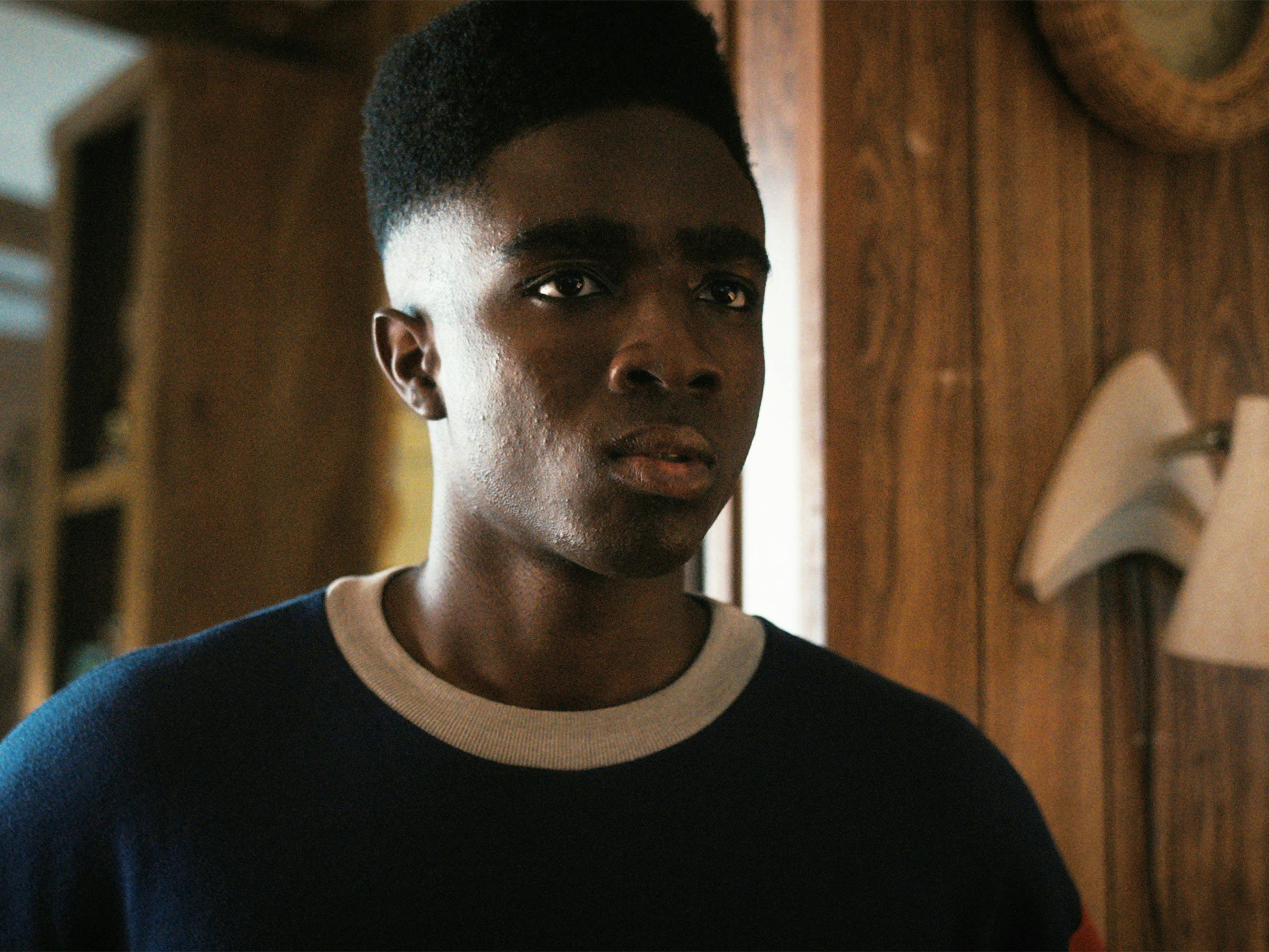 Lucas Sinclair (Caleb McLaughlin) wears a navy shirt lined with white.