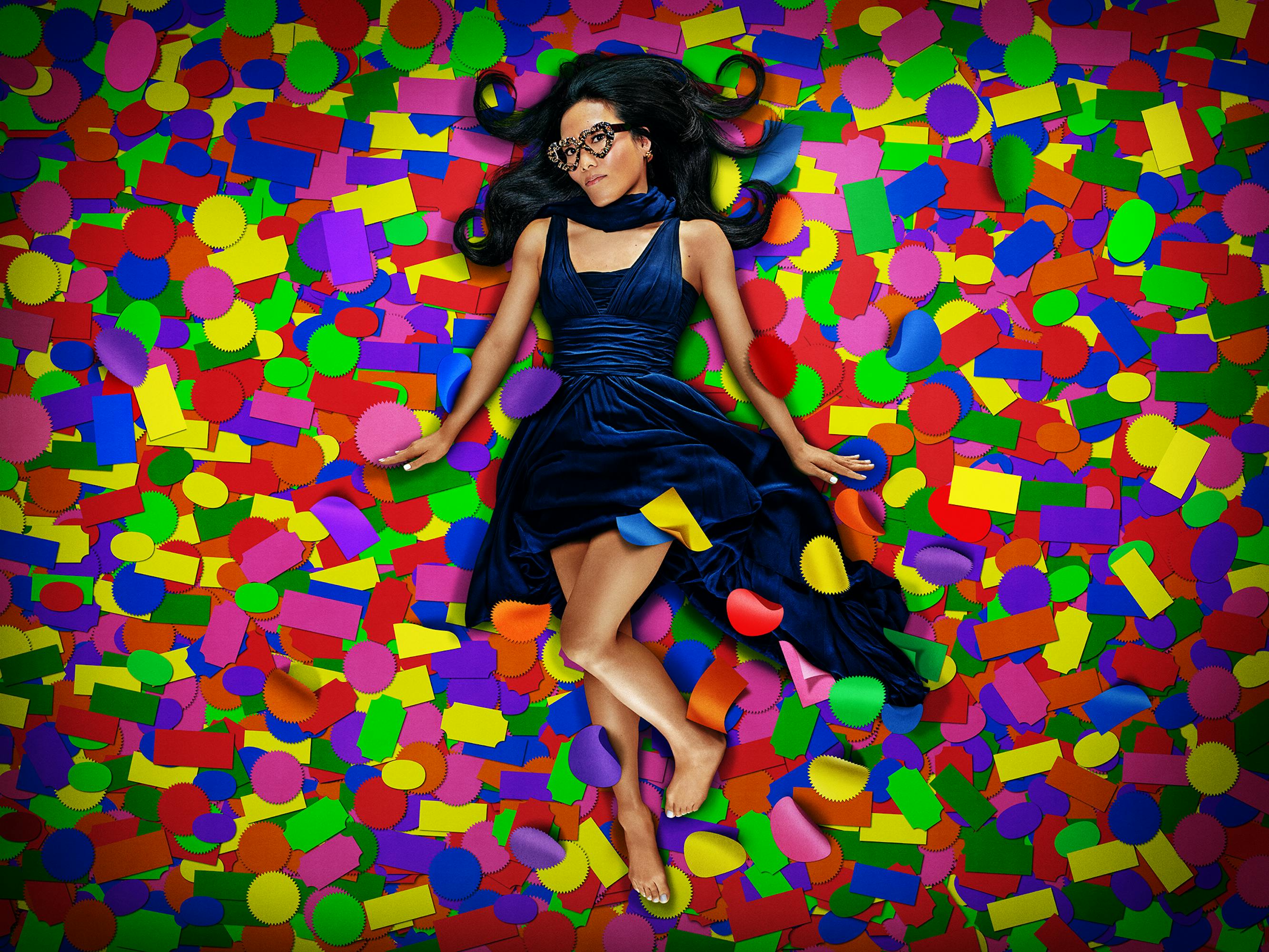 Ali Wong wears a blue velvet dress and lies in a pile of stickers.