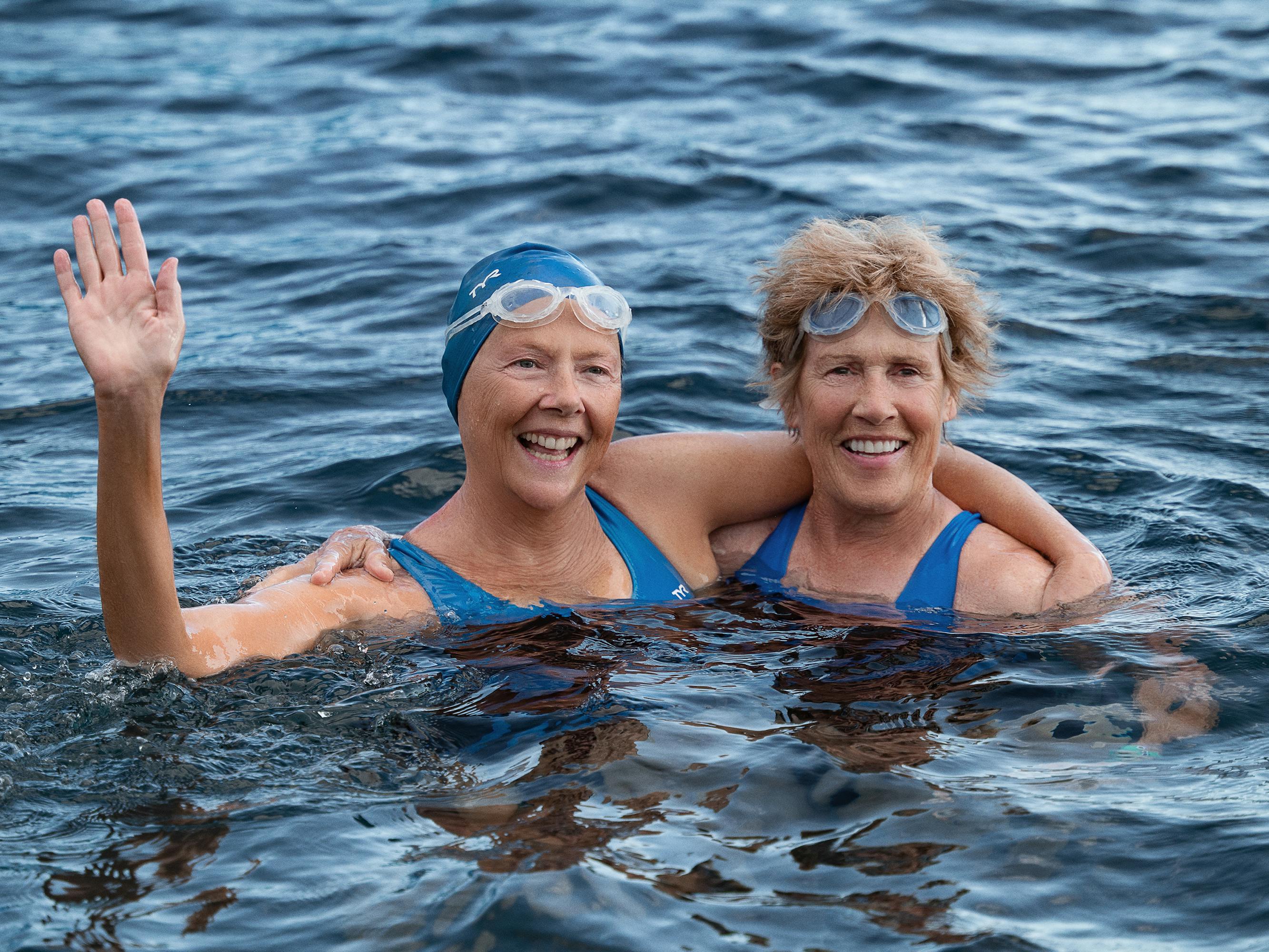 Annette Bening and Diana Nyad tread water and wear matching blue bathing suits and goggles.
