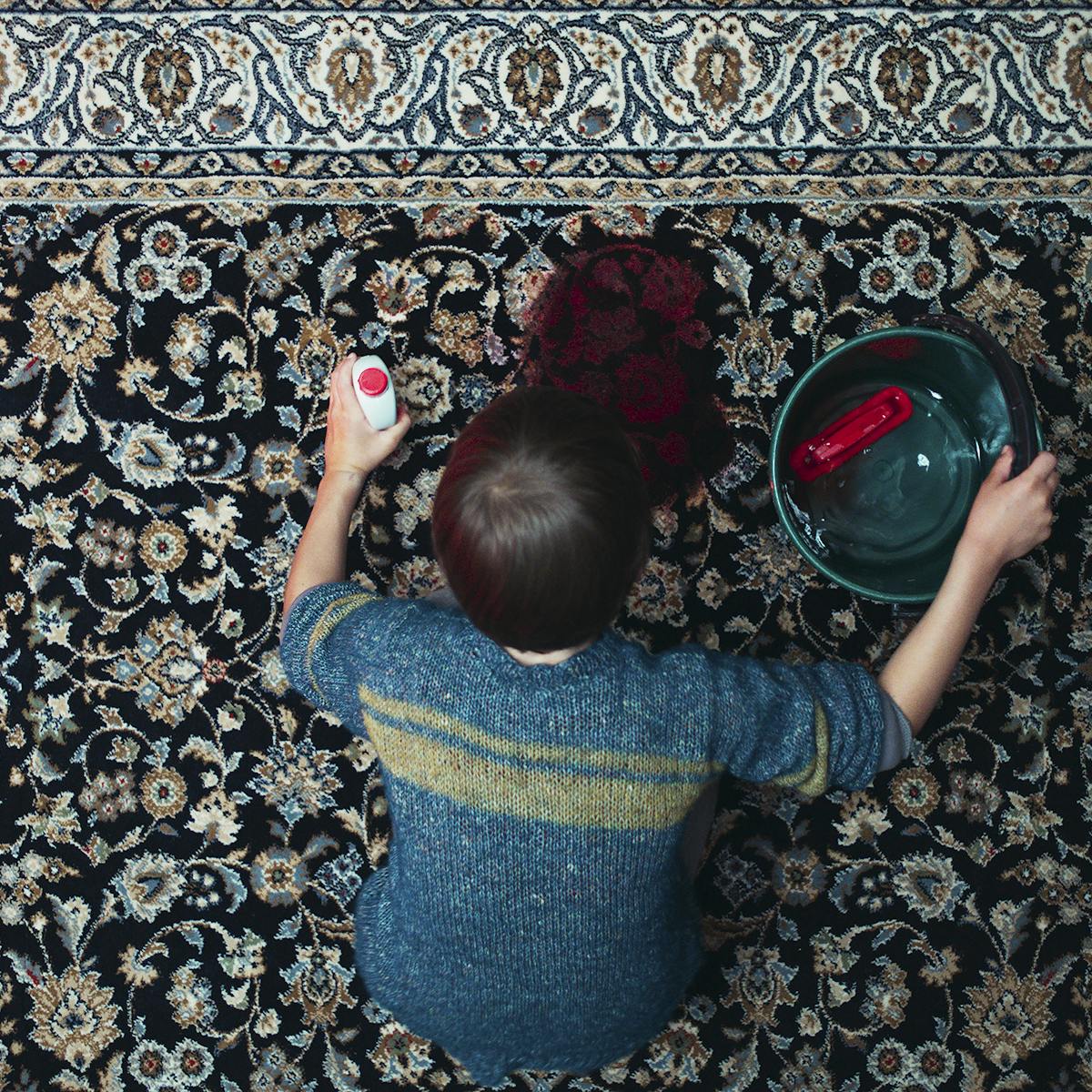 Jonathan (Sammy Schrein) cleans up a blood stain on an patterned rug.