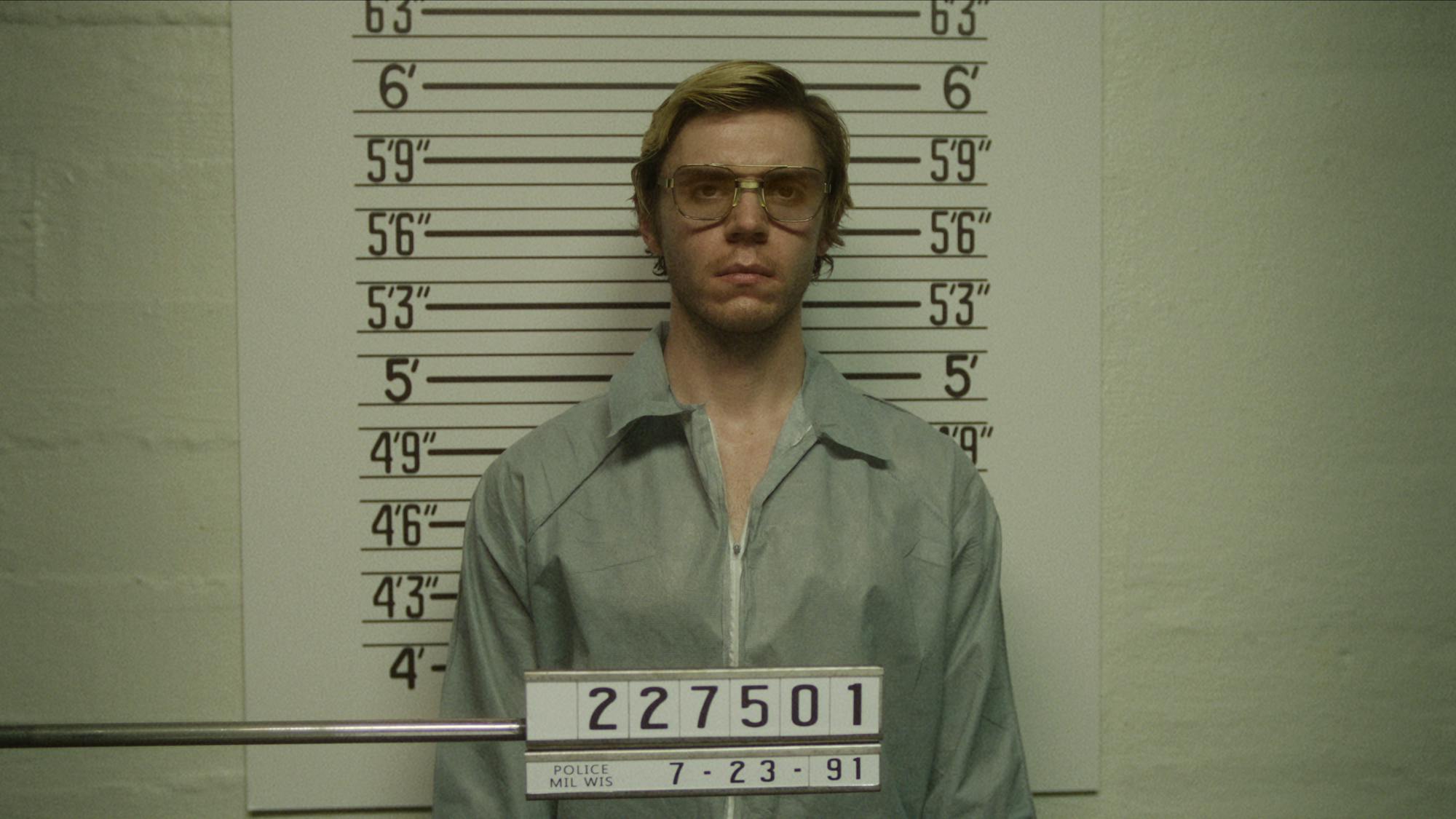 Jeffrey Dahmer (Evan Peters) wears grey prison garb and gets his mugshot taken.