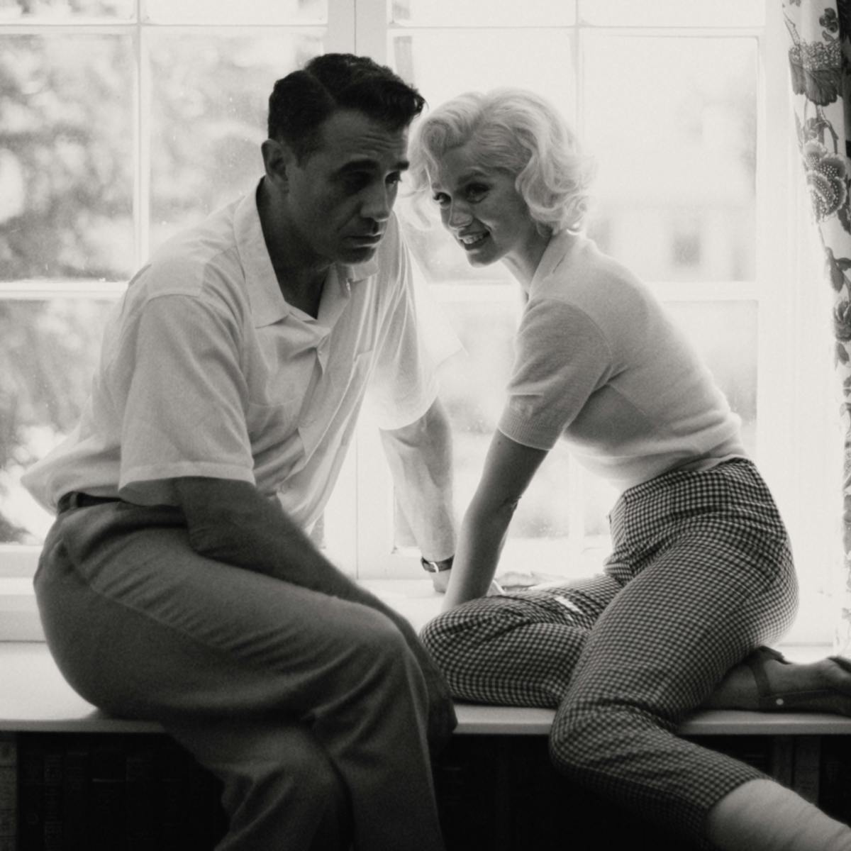 Bobby Cannavale and Marilyn Monroe sit in a window sill together in this black-and-white shot.