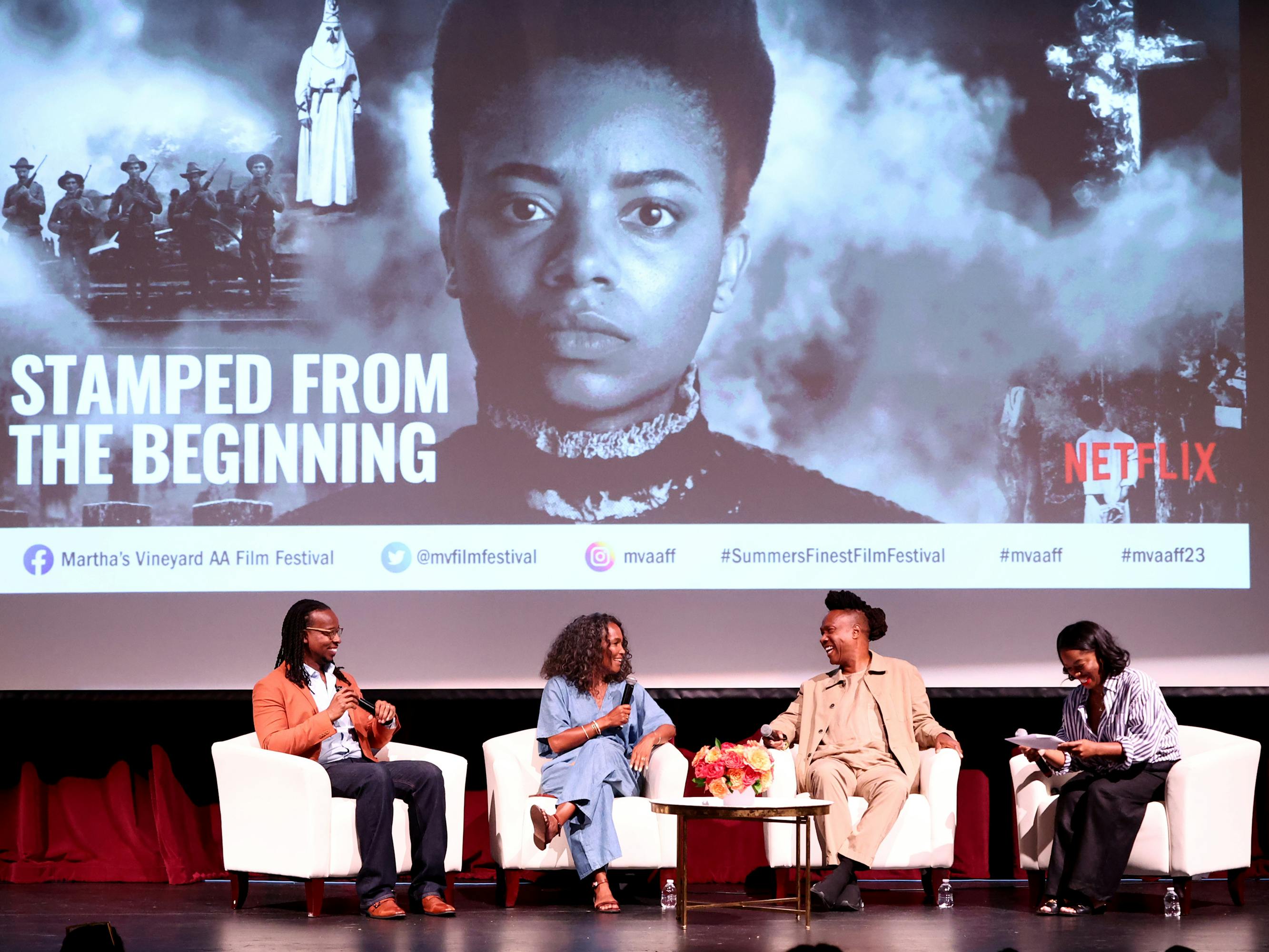 Four people sit onstage in conversation about the film Stamped from the Beginning (the title is projected behind them).