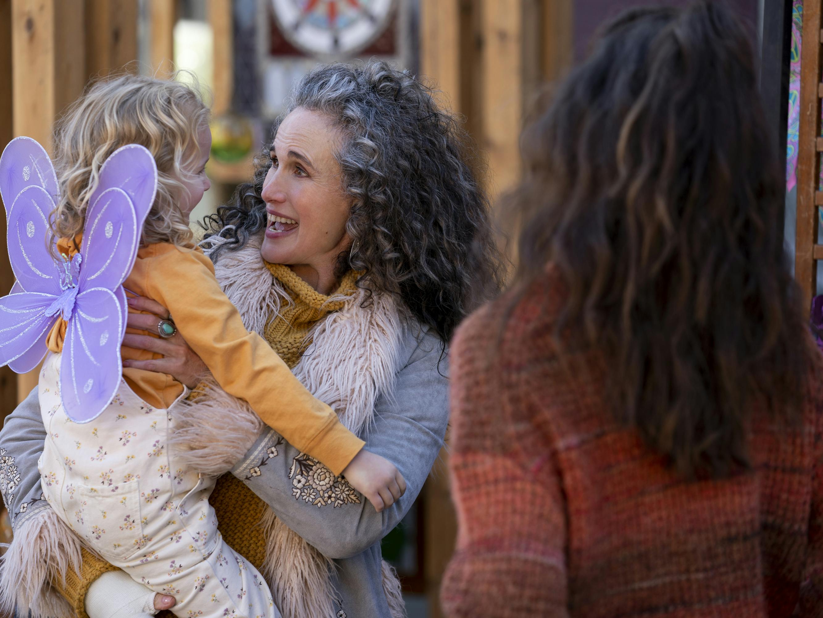 Andie MacDowell, Rylea Nevaeh Whittet, and Margaret Qualley in Maid. MacDowell wears a furry jacket, Whittet wears purple fairy wings, and Qualley wears a red sweater.