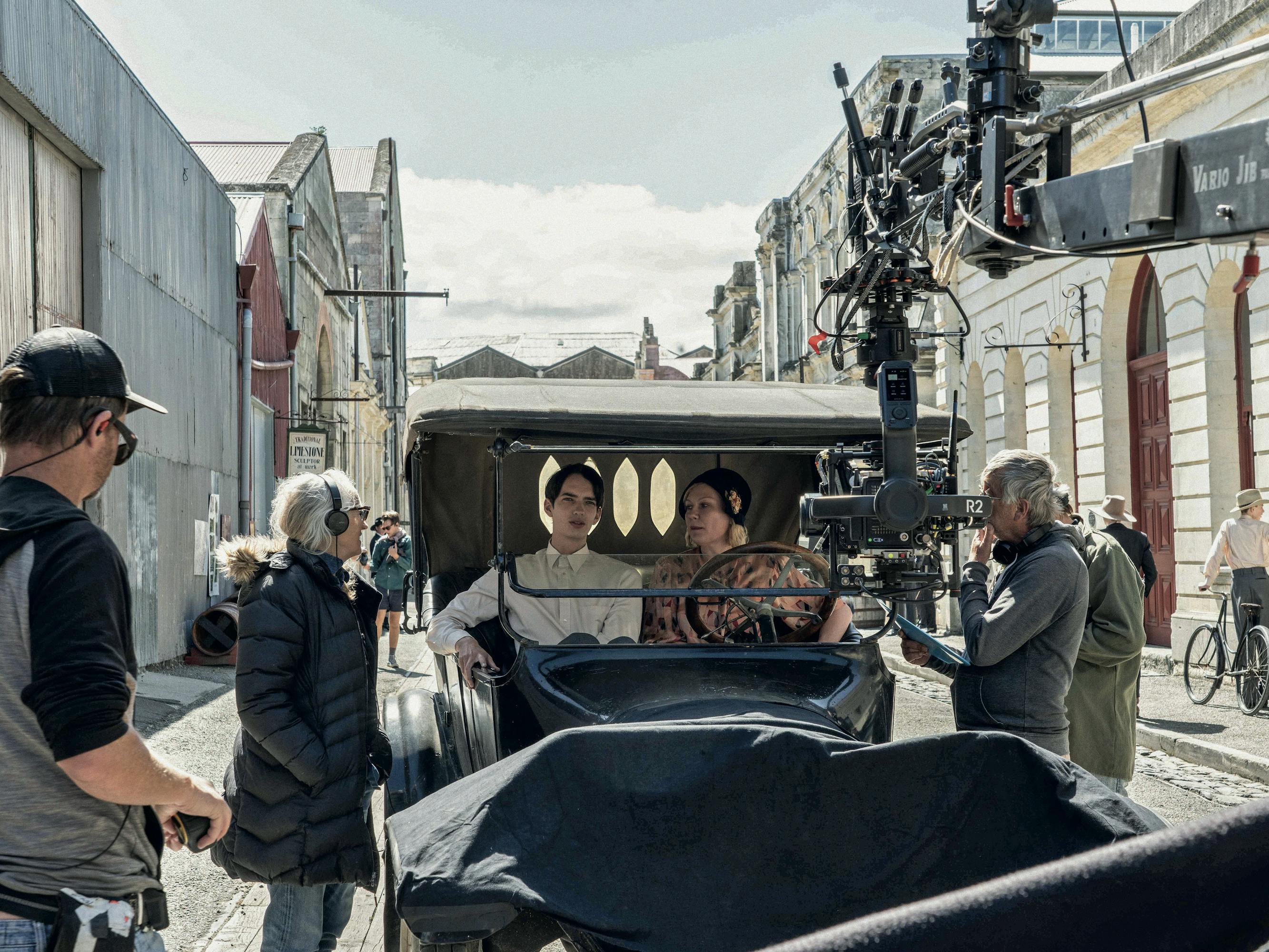 Jane Campion and The Power of the Dog crew stand around a buggie in which Kirsten Dunst and Kodi Smit-McPhee sit.