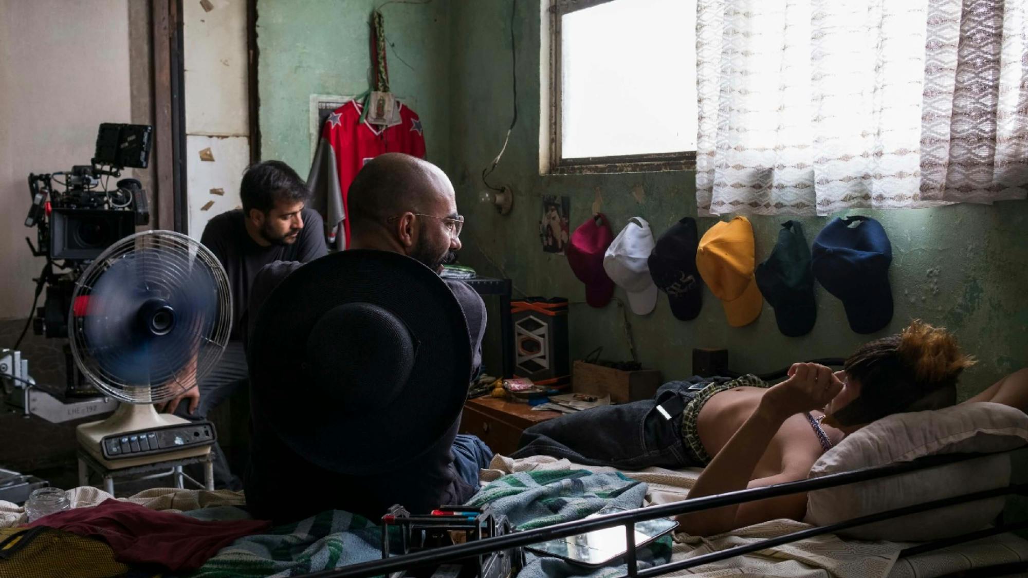 The cinematographer, director, and actor appear in a cramped room with peeling paint, crowded with the character Ulises’s personal belongings.