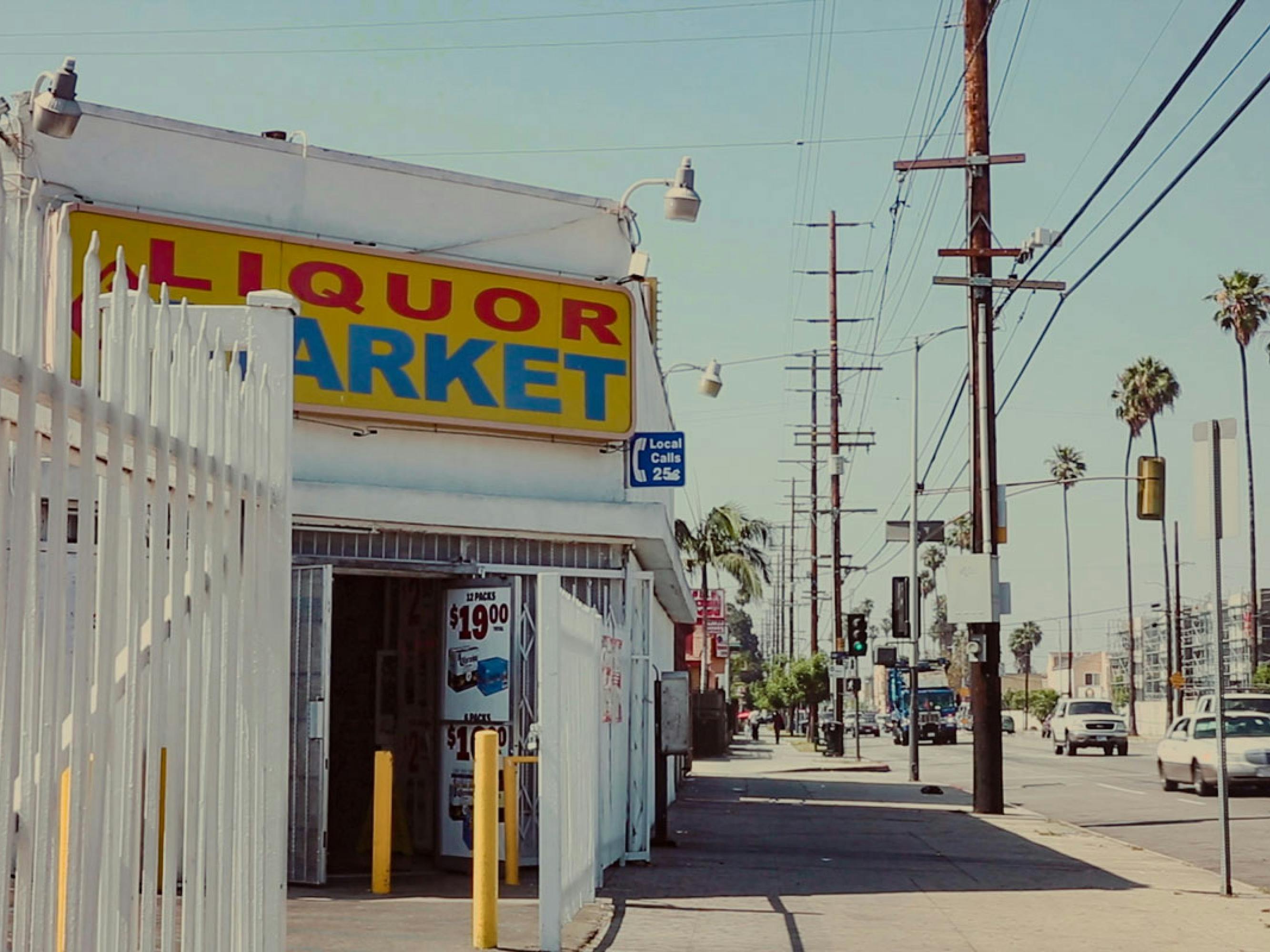 A liquor market on a sunny, whitewashed Los Angeles street.