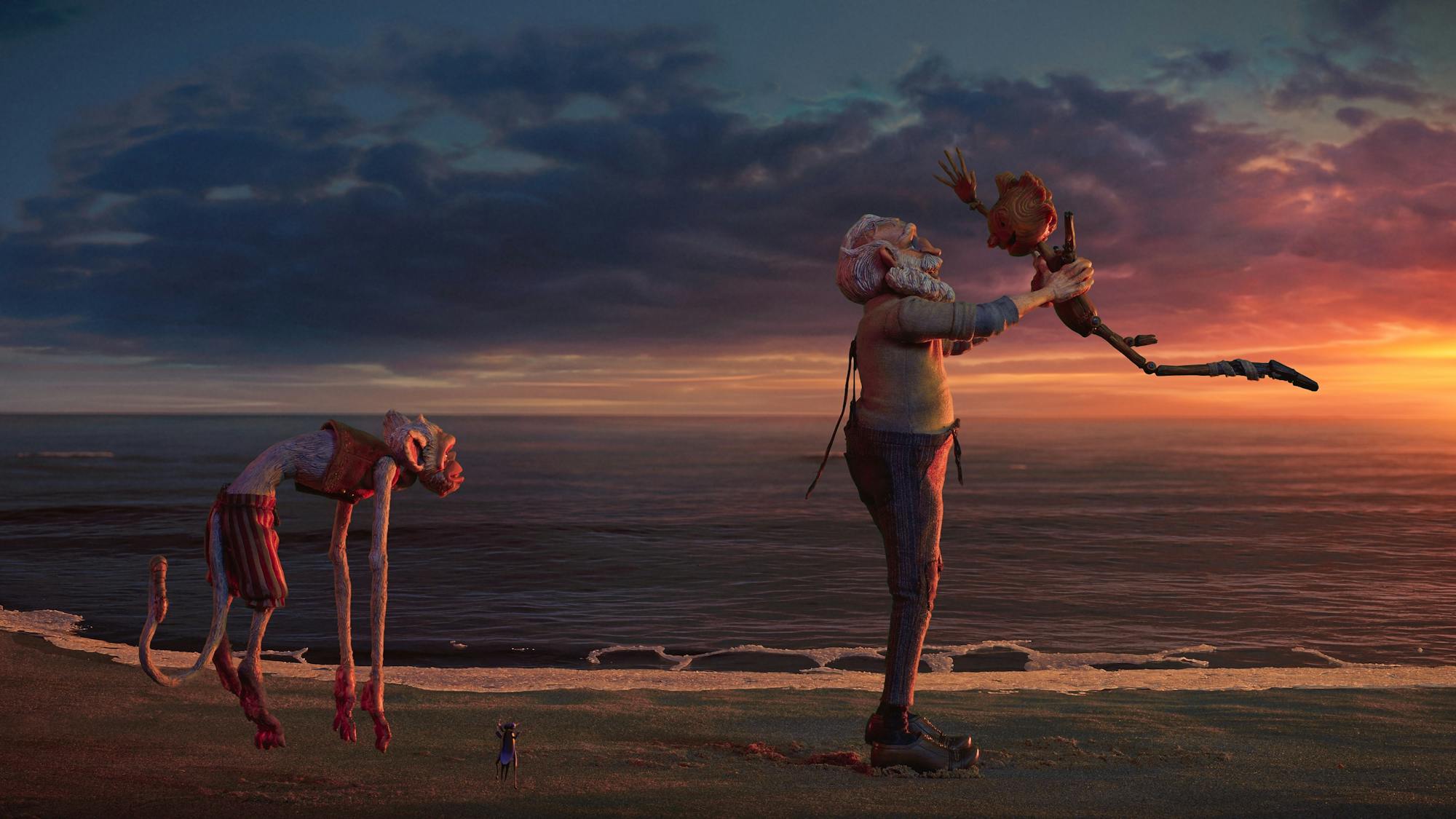 Spazzatura (Cate Blanchett) stands behind Geppetto (David Bradley) as he swings Pinocchio (Gregory Mann) into the air, lit by an orange-purple sunset.