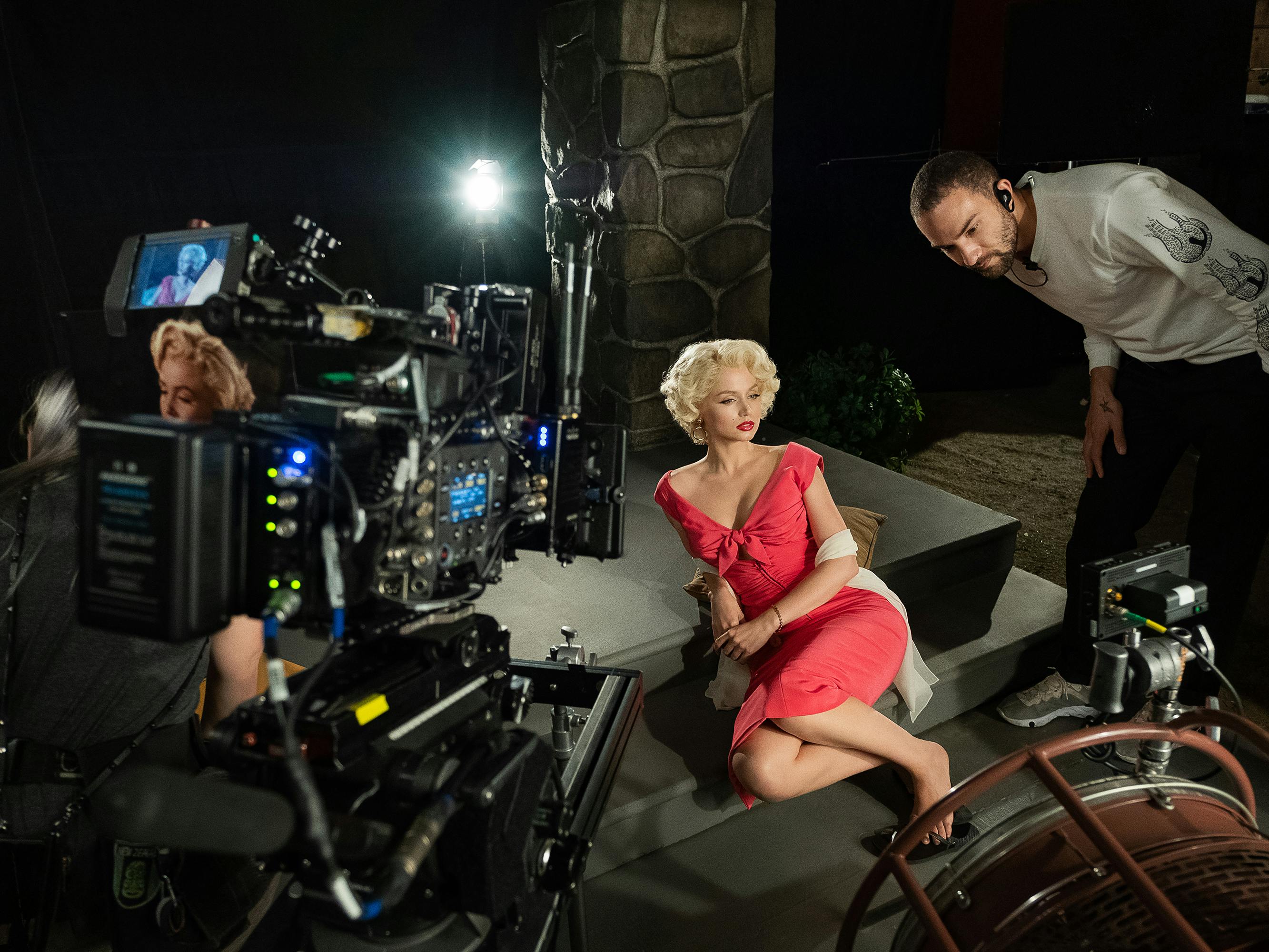 Ana de Armas behind the scenes of Blonde. She wears a v-necked red dress.