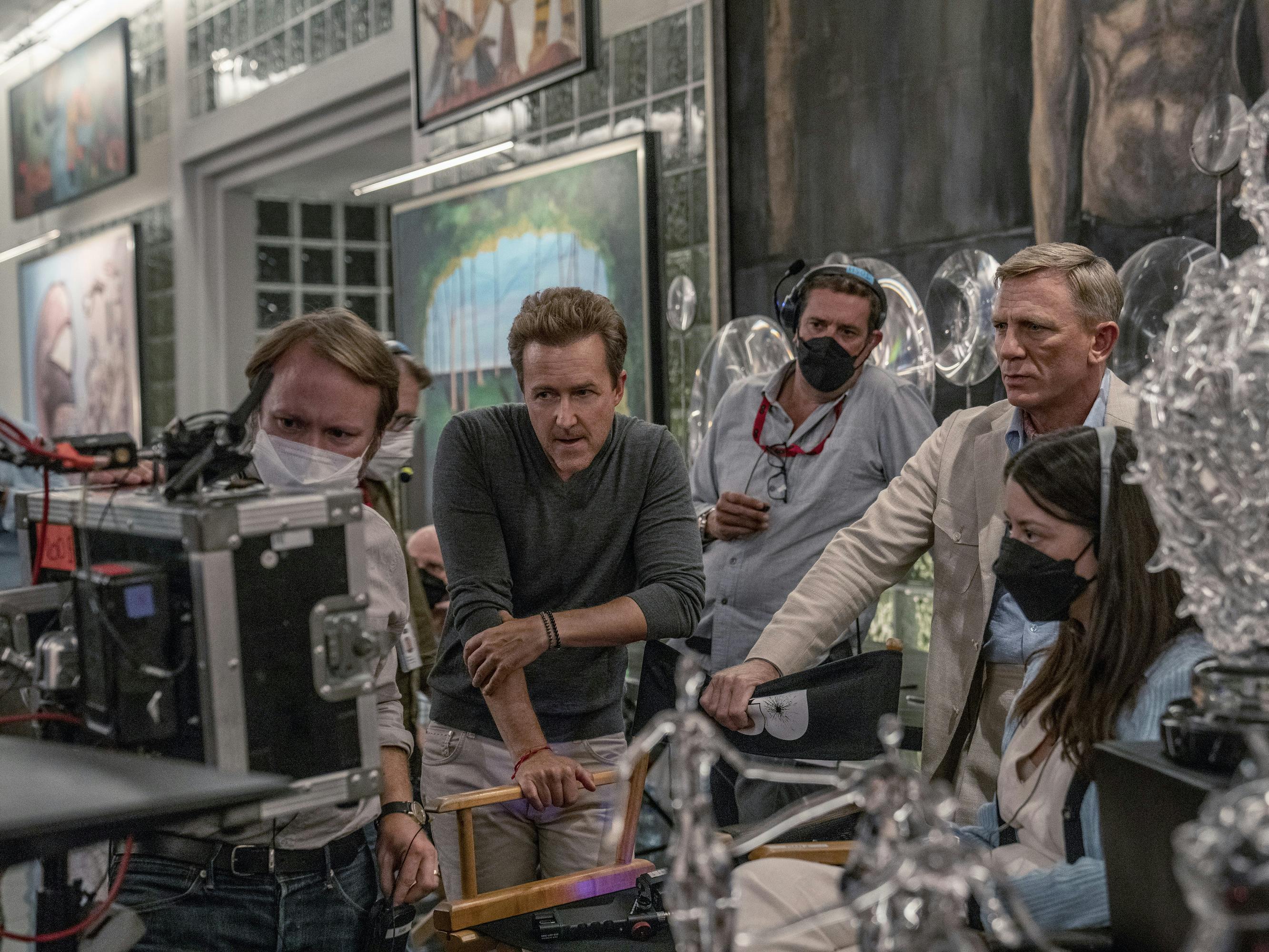 Rian Johnson, Edward Norton, Daniel Craig, and Glass Onion crew members stand around a monitor.