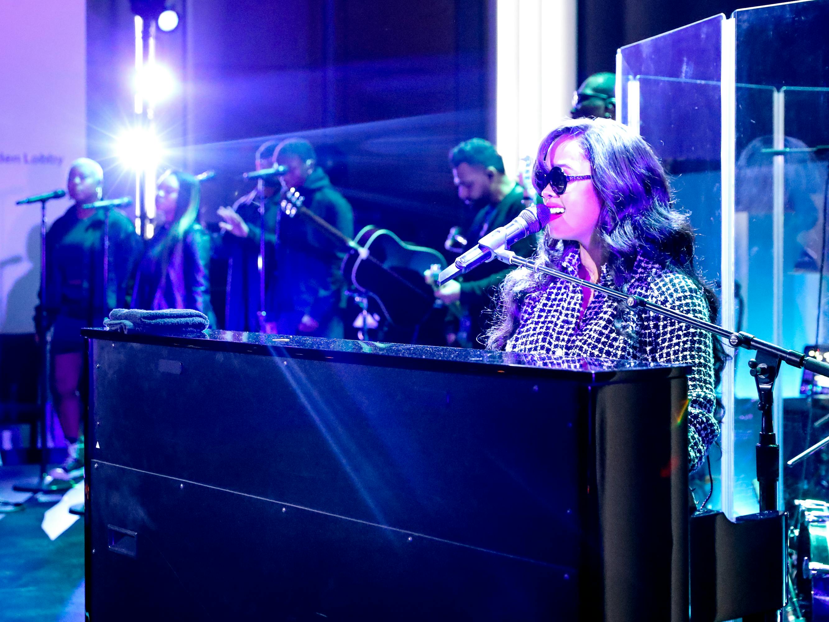 H.E.R. wears circular glasses and a patterned top.