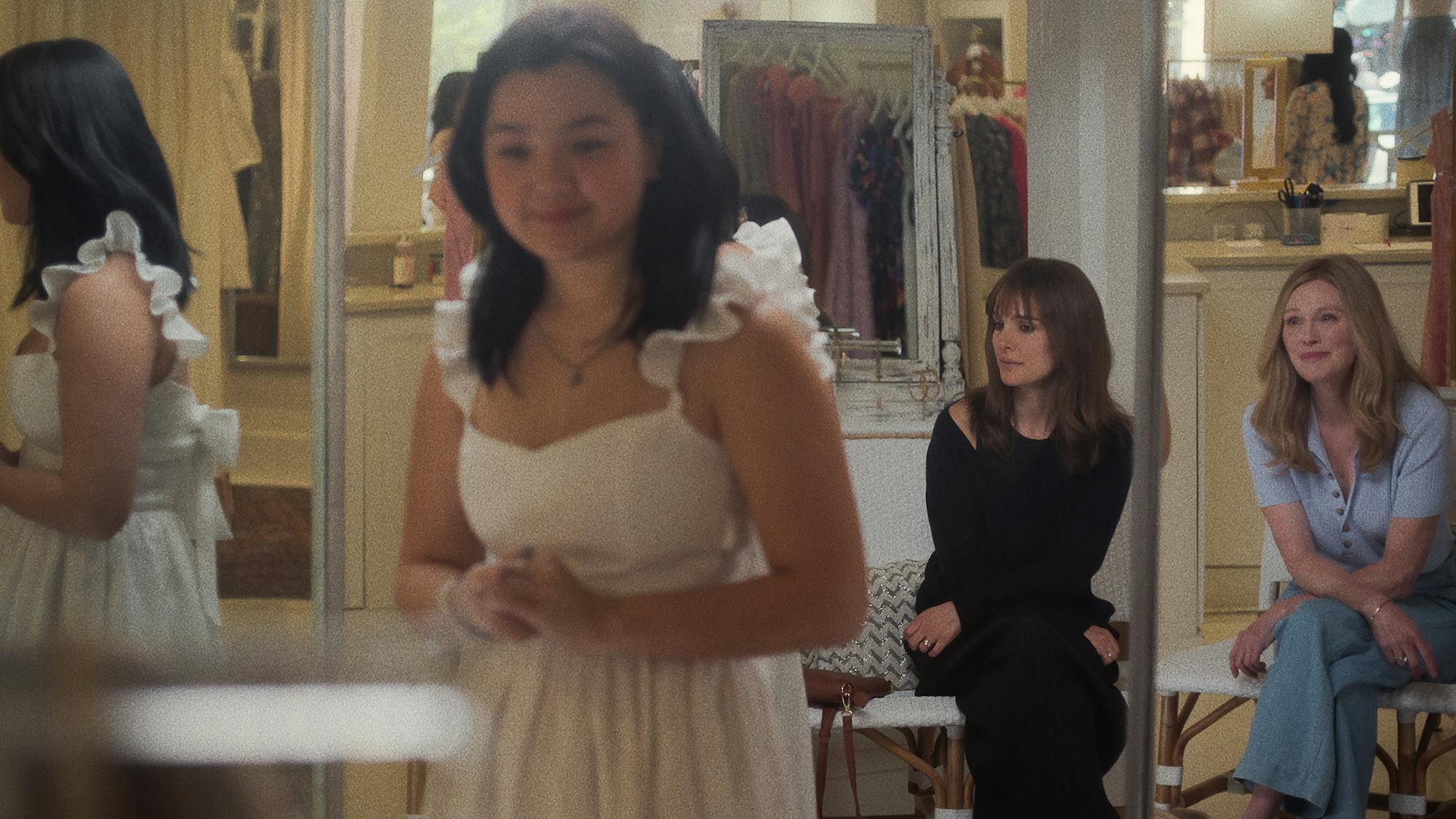 Mary Atherton-Yoo (Elizabeth Yu) tries on a white dress as Elizabeth Barry (Natalie Portman) and Gracie Atherton-Yoo (Julianne Moore) sit nearby and look on.