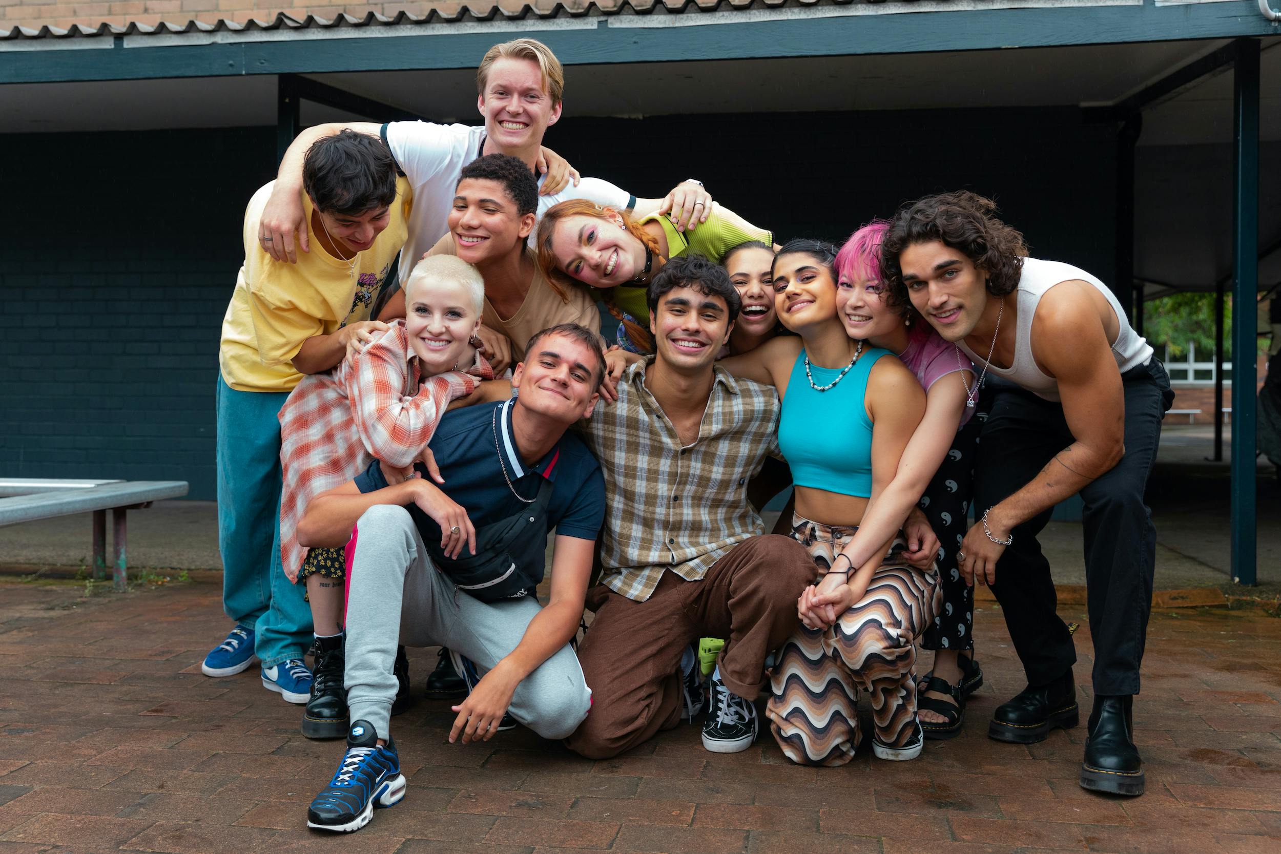 The Heartbreak High cast huddles together in colorful outfits.