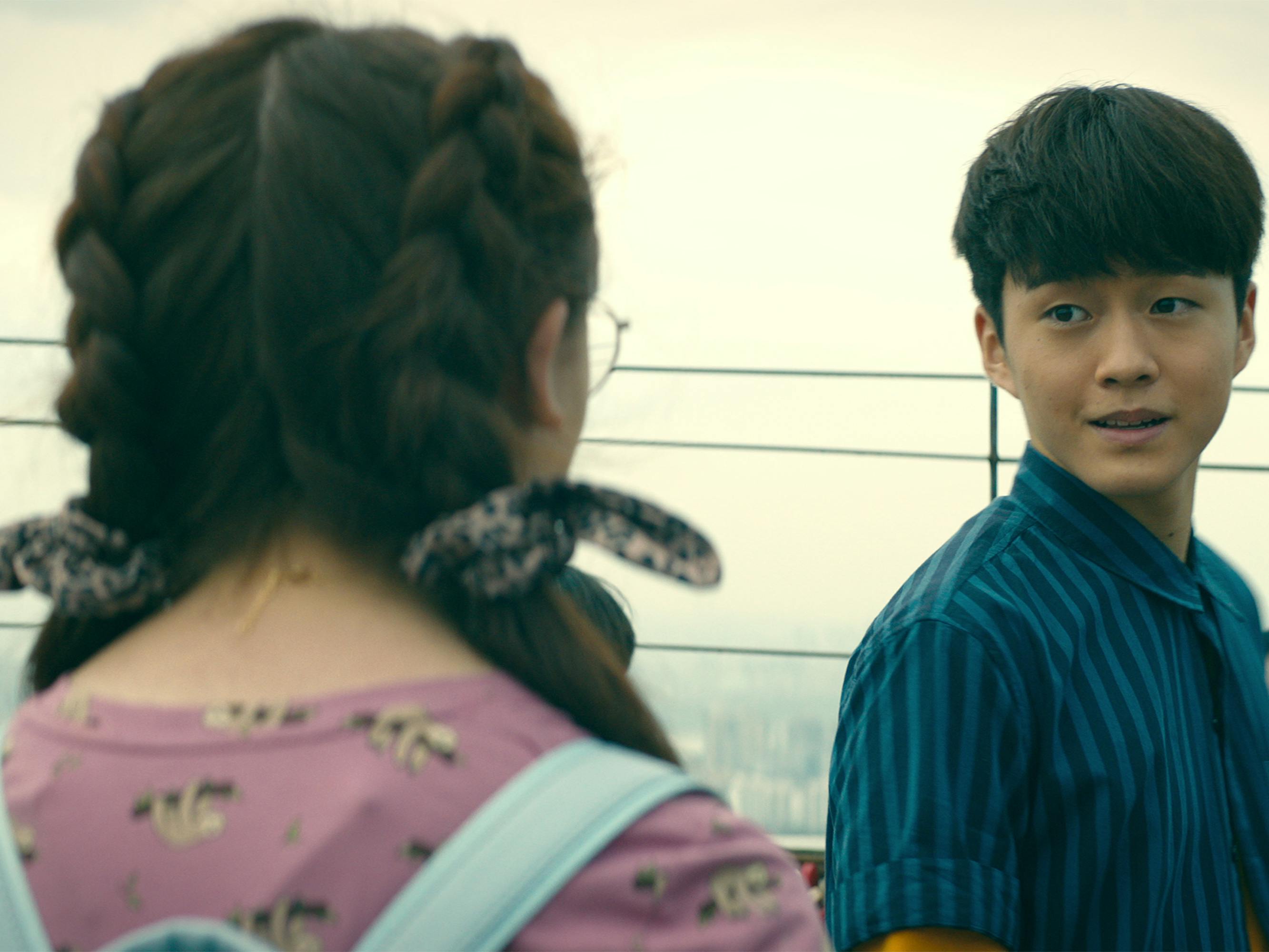 Kitty (Anna Cathcart) has her back to the camera as she looks at Dae (Jeon Ho-young), who wears a navy shirt.