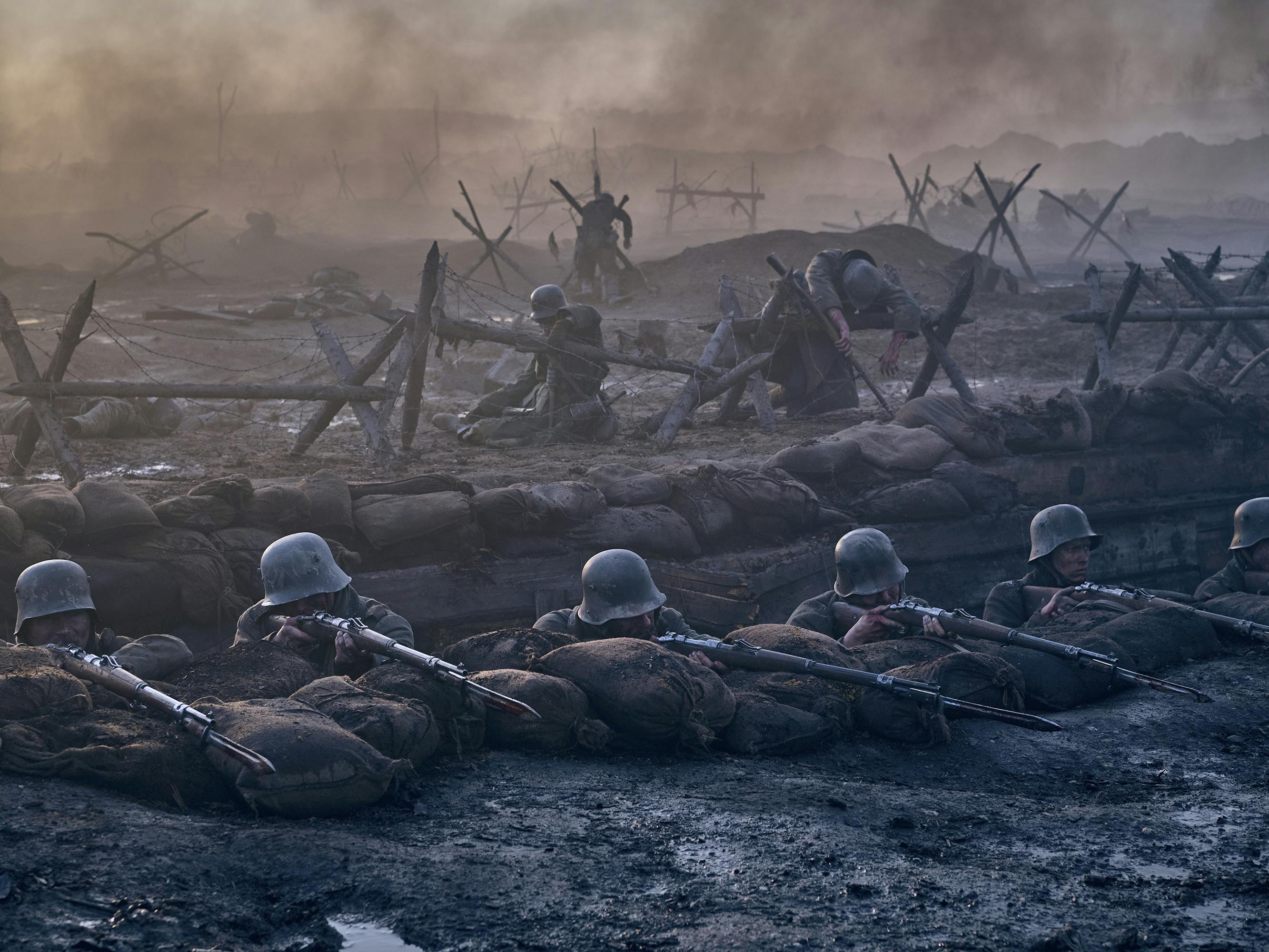 Paul Bäumer (Felix Kammerer) and other soldiers crouch in a trench with their guns at the ready.
