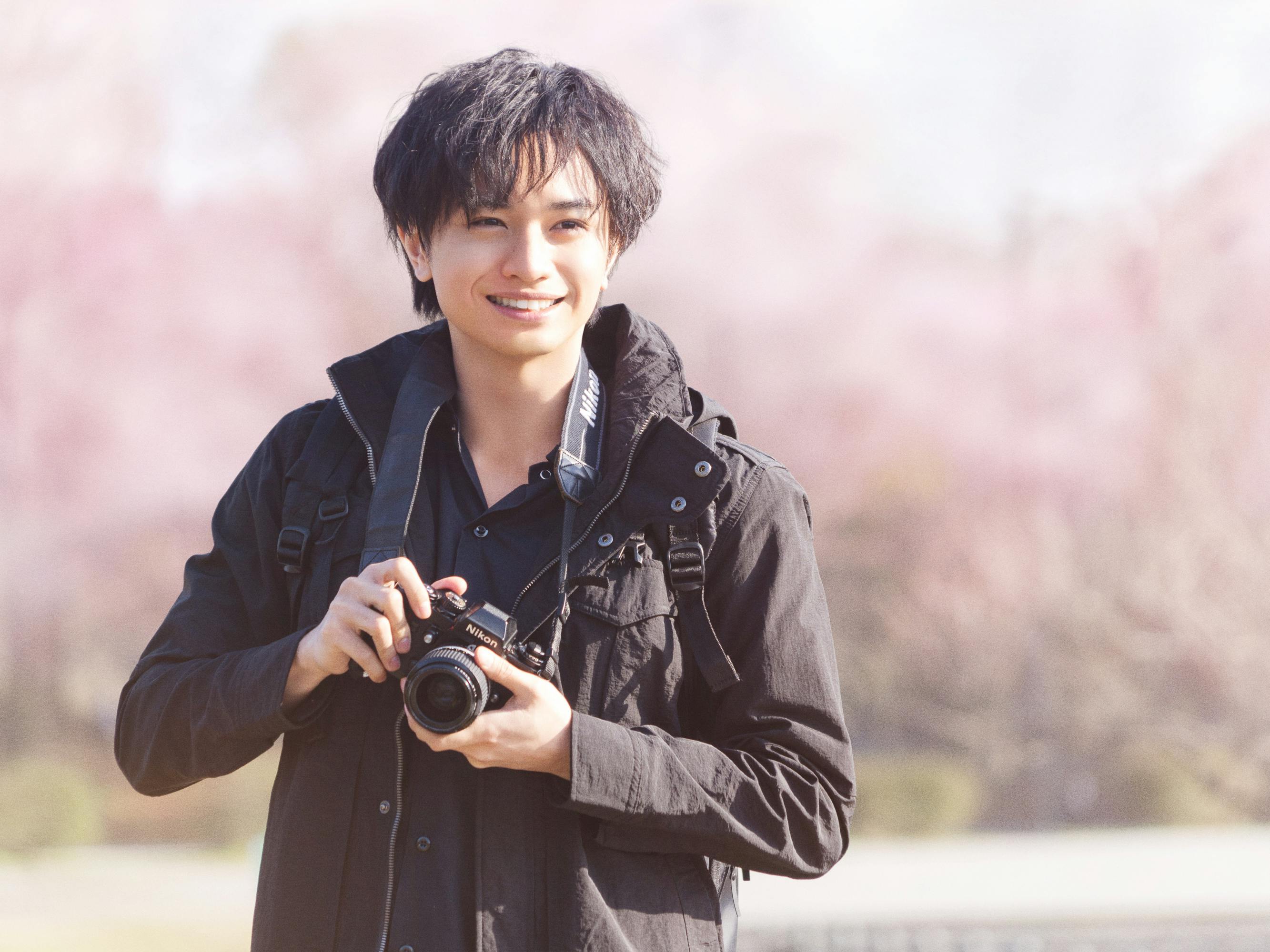 Kento Nakajima wears all black and holds his camera around his neck.