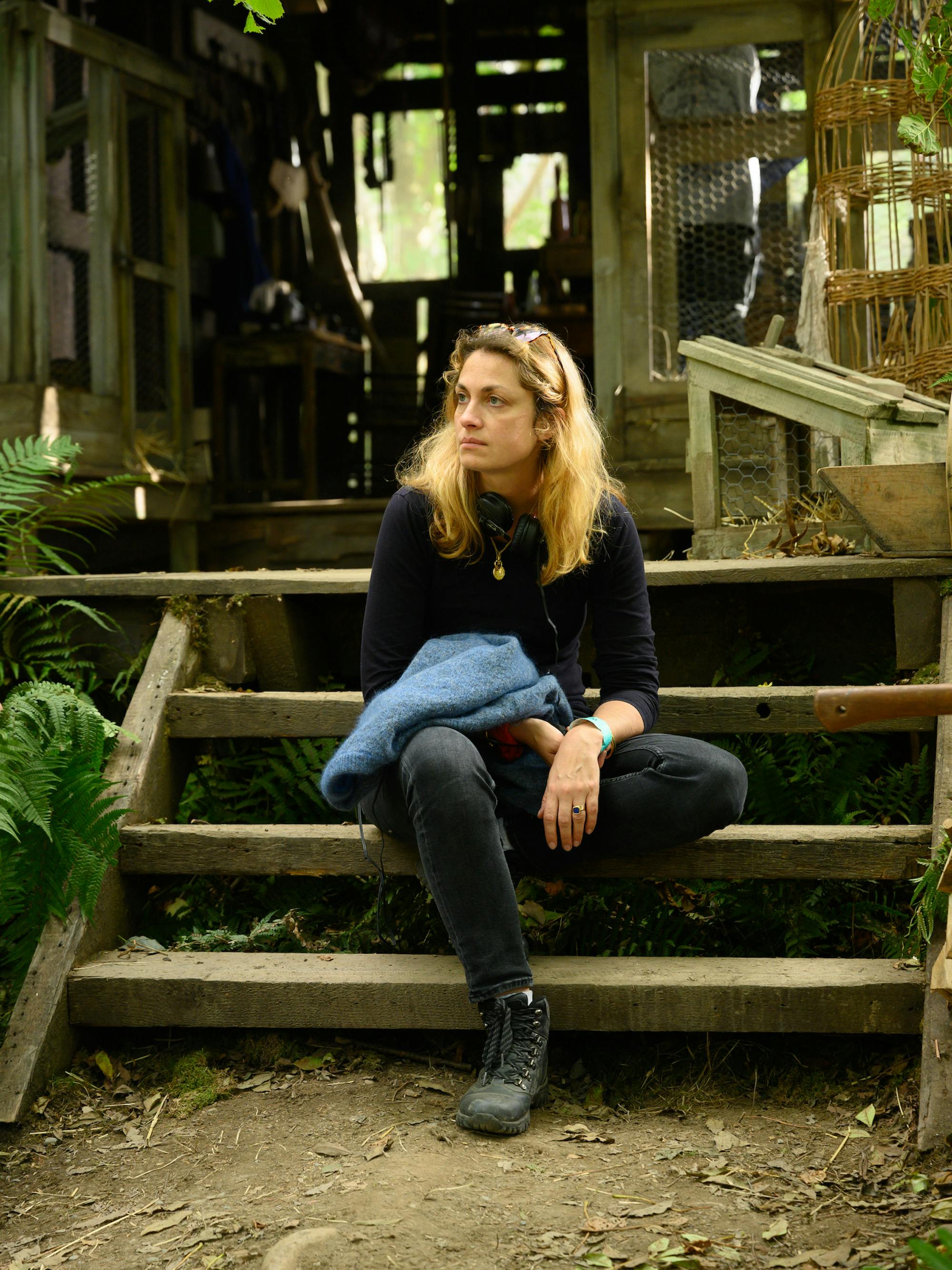 Laure de Clermont-Tonnerre wears a black top and black jeans, and sits on some wooden steps.