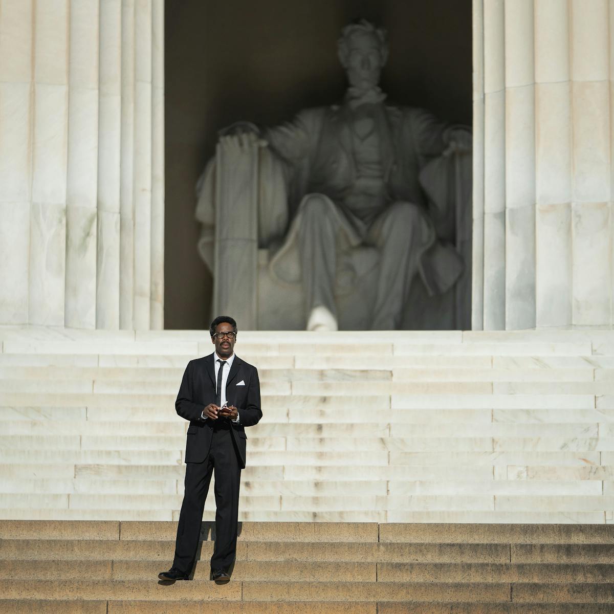 Bayard Rustin (Colman Domingo) wears a dark suit and stands at the Lincoln Memorial.