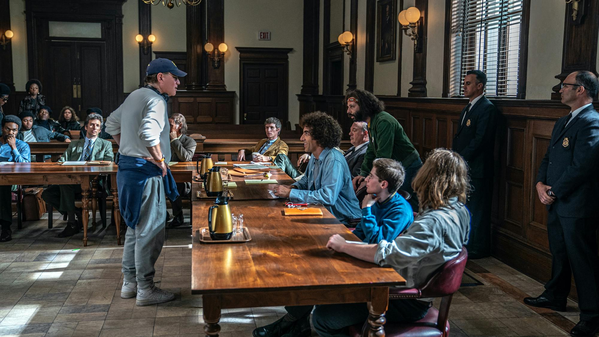 Aaron Sorkin stands across from his cast as he directs them in a courtroom scene in The Trial of the Chicago 7. Watch as he compares himself to an adorable animal...