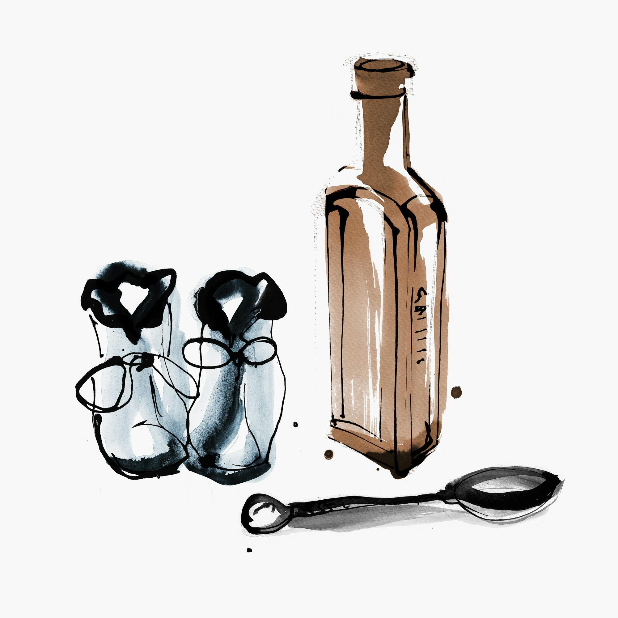 Some baby shoes next to a bottle of tonic and spoon.