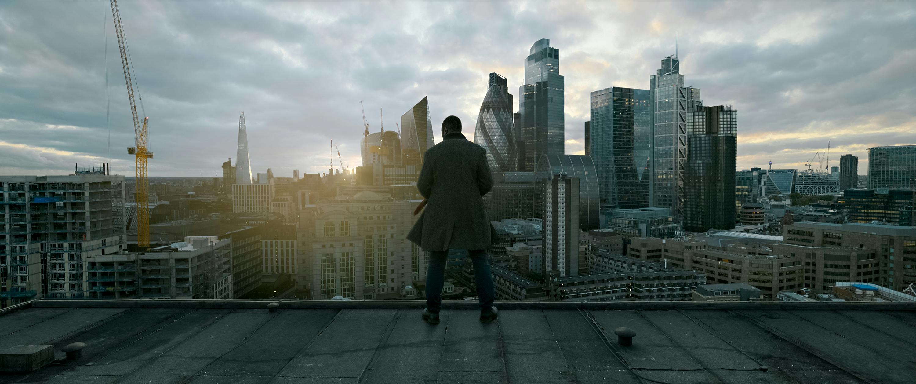 John Luther (Idris Elba) stands on a roof overlooking London, as the sun crests behind the skyline.