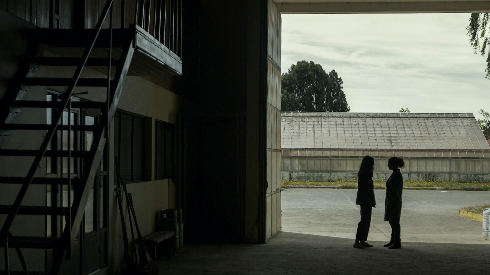 Amanda (María Valverde) and Carola (Dolores Fonzi) stand across from each other in an empty barn. Their figures are hardly discernible in this shadowy space. 